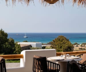 a patio with tables and chairs overlooking the ocean