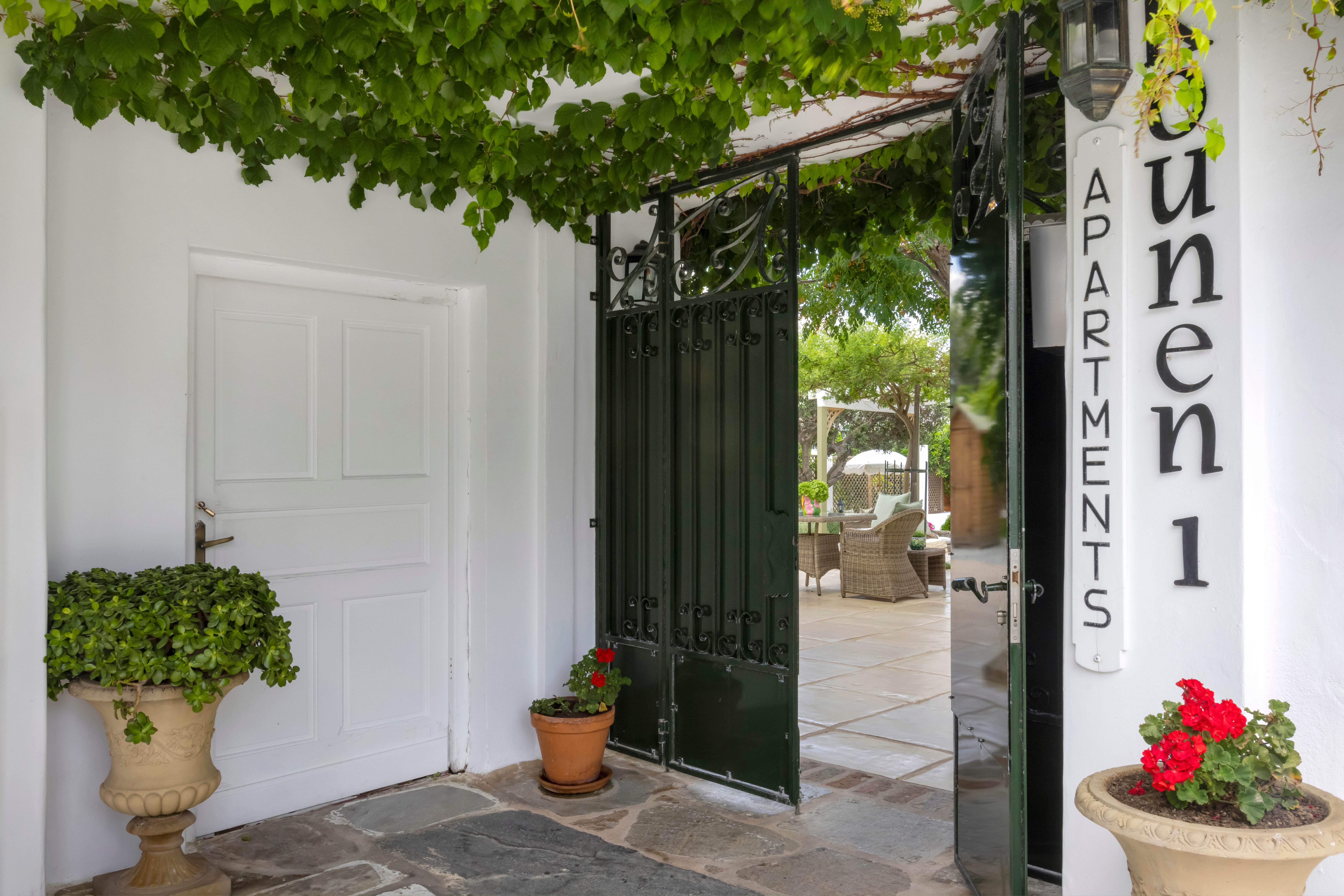 a white building with green doors and plants
