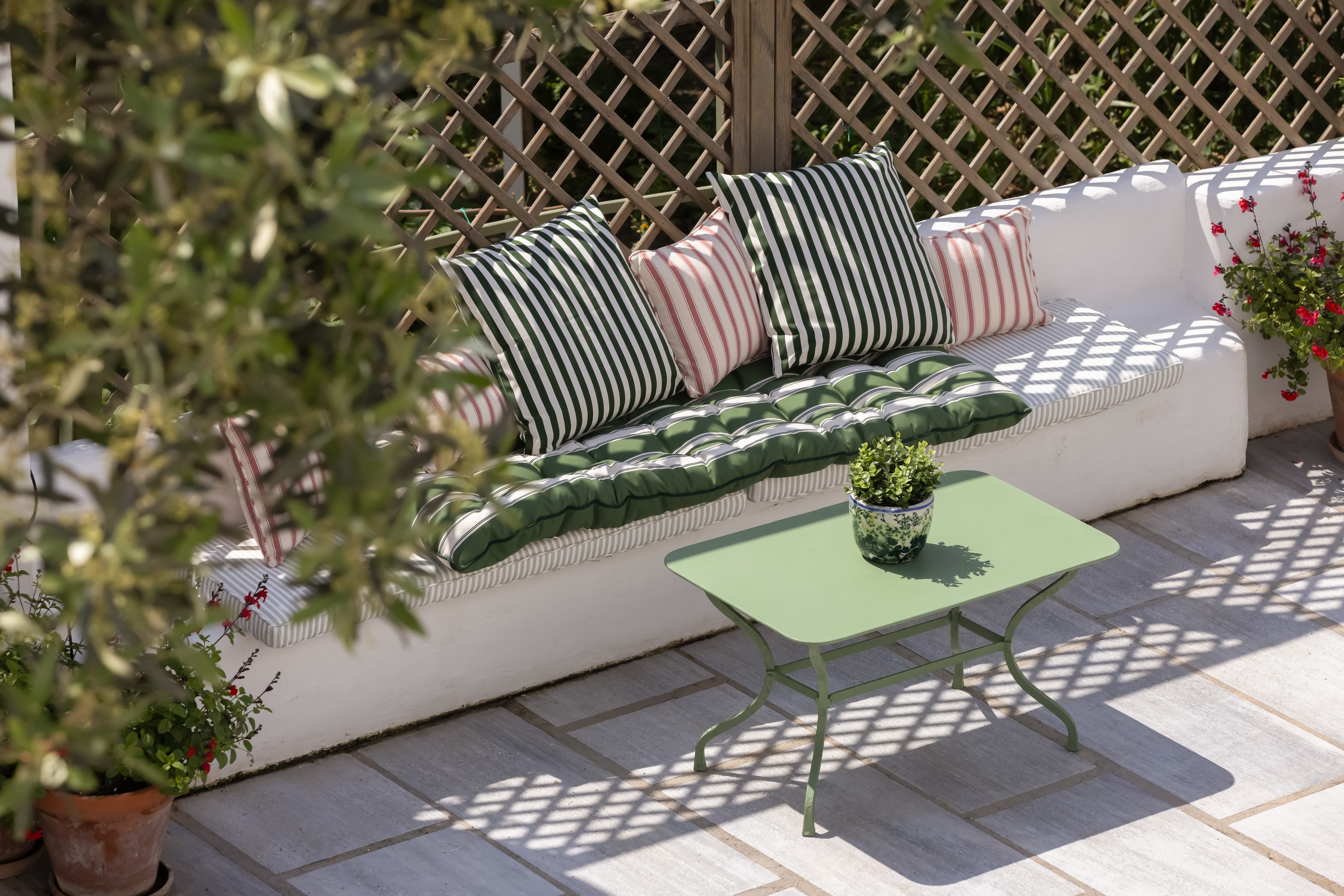 a patio with a green table and a bench