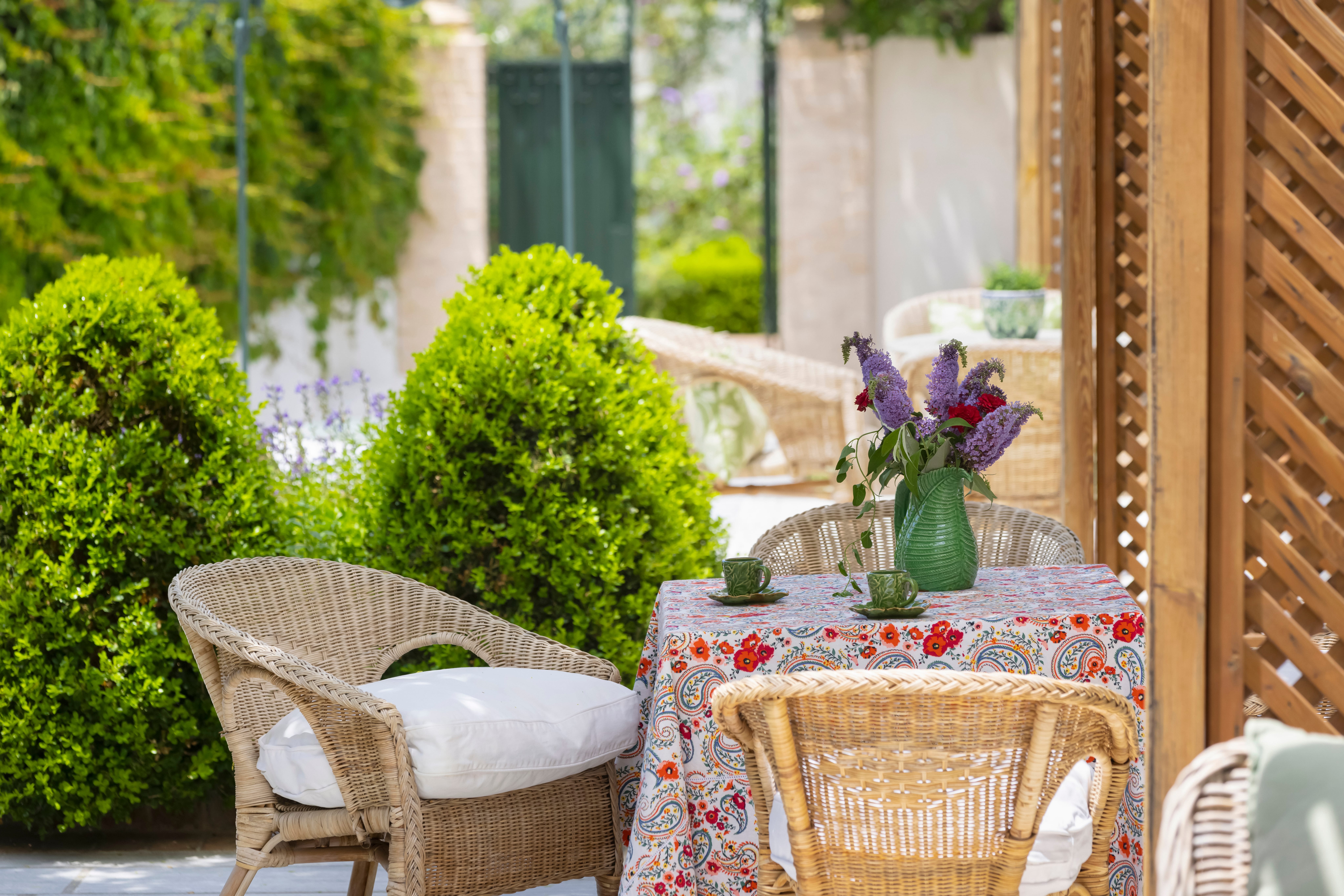 a table and chairs outside with a vase of flowers