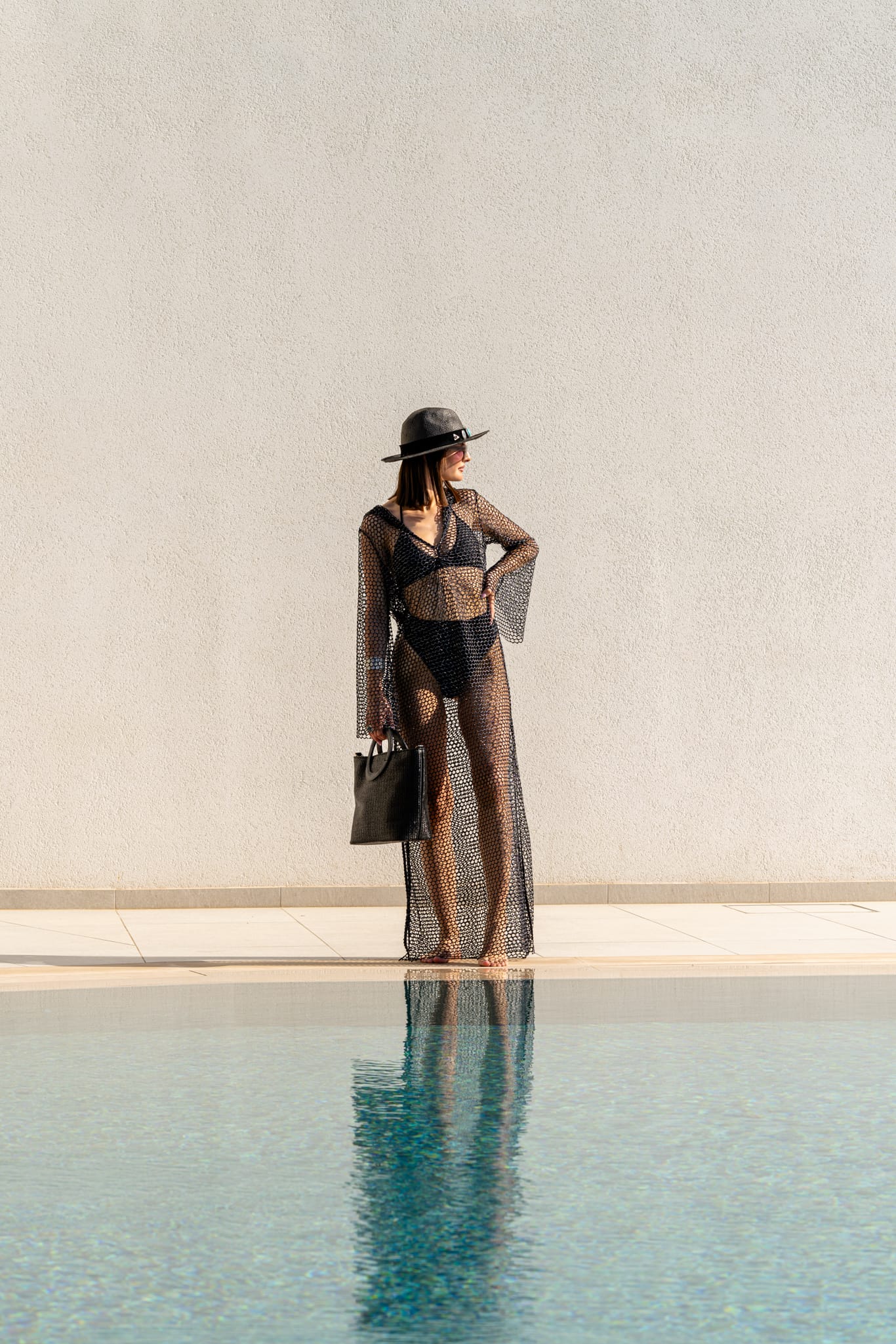 a person in a black swimsuit and hat standing by a pool