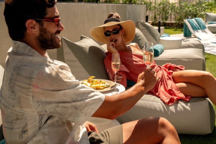 a person holding a glass of wine and a person sitting on a chair