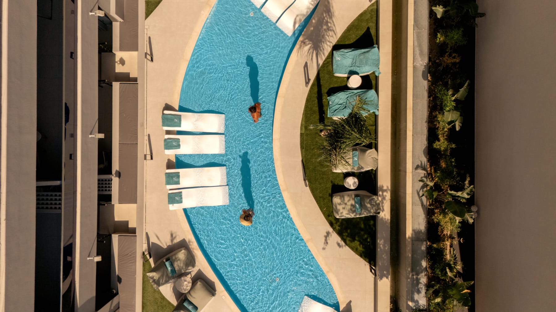 a pool with lounge chairs and a person swimming in it
