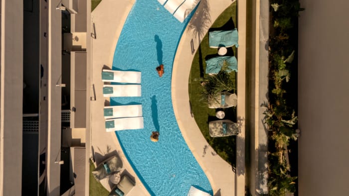 a pool with lounge chairs and a person swimming in it