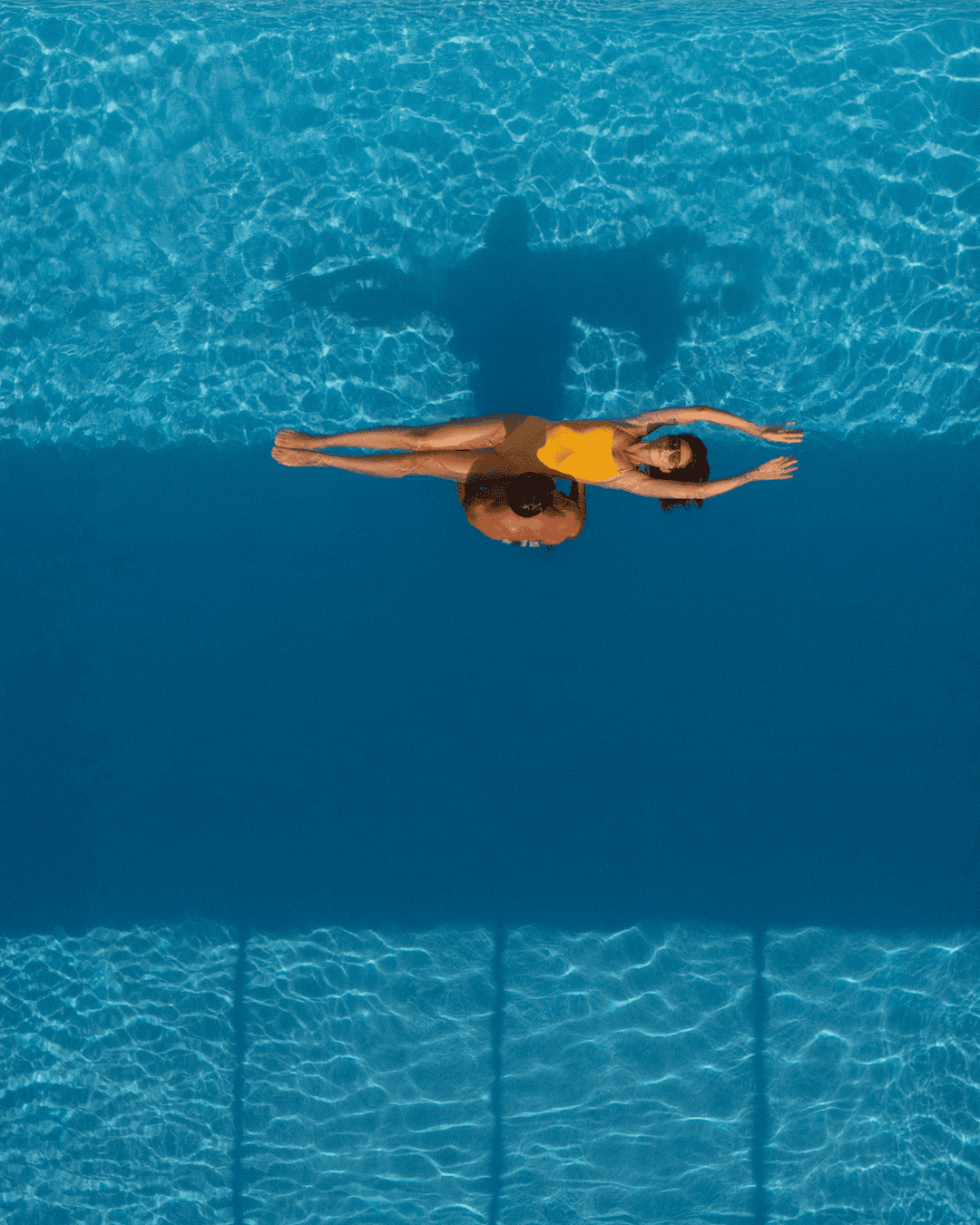 a person in a yellow swimsuit floating in a pool