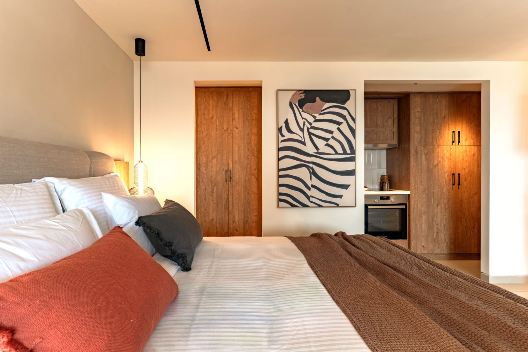 a bed with a brown blanket and a painting on the wall