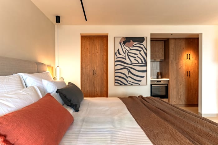 a bed with a brown blanket and a painting on the wall