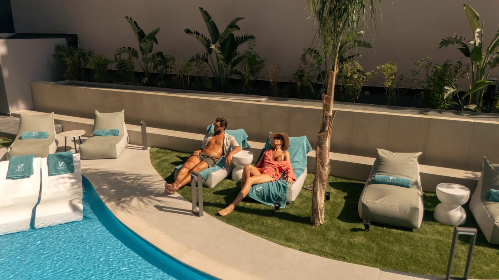 a person and person sitting on chairs by a pool