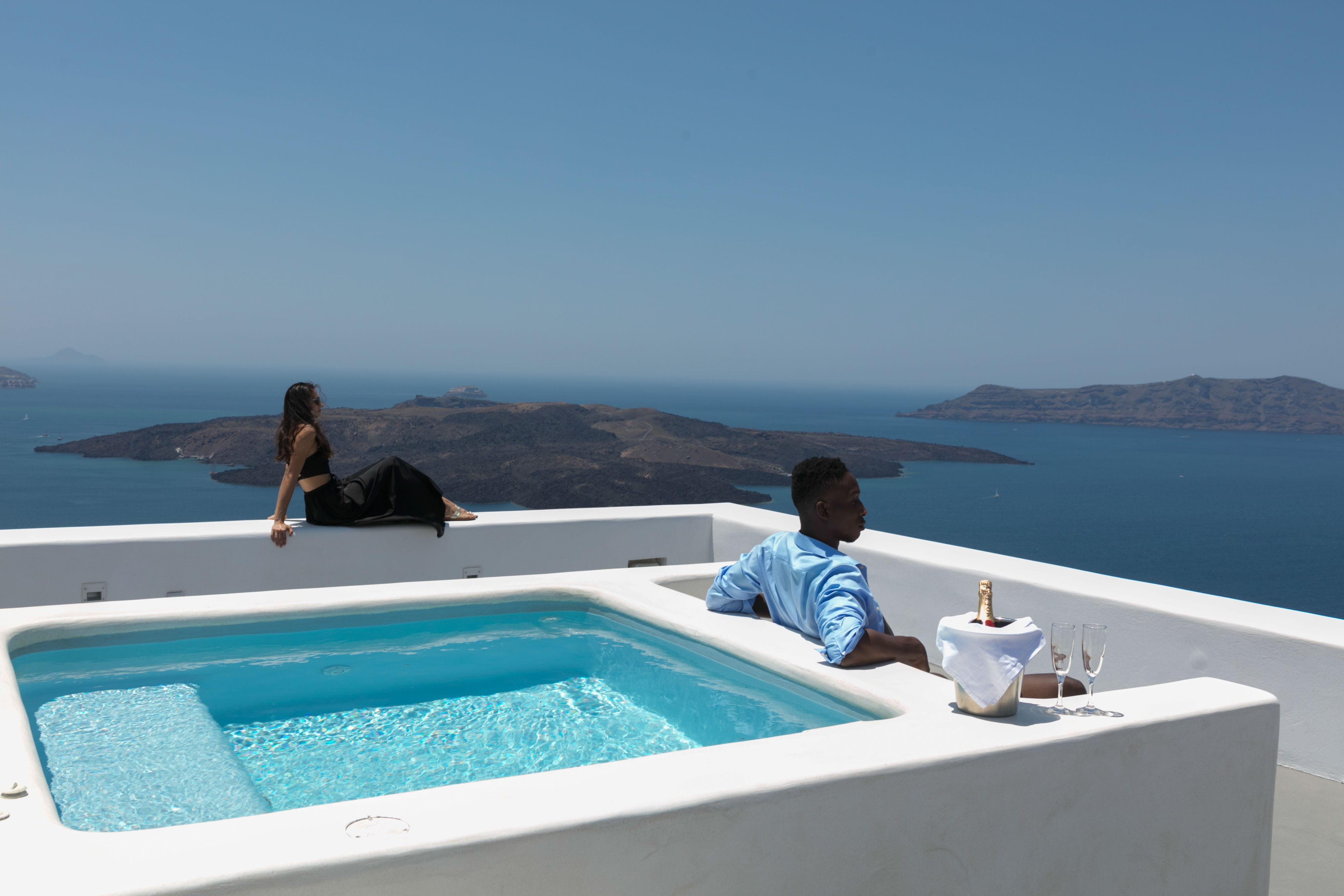a person and person sitting on a rooftop with a pool