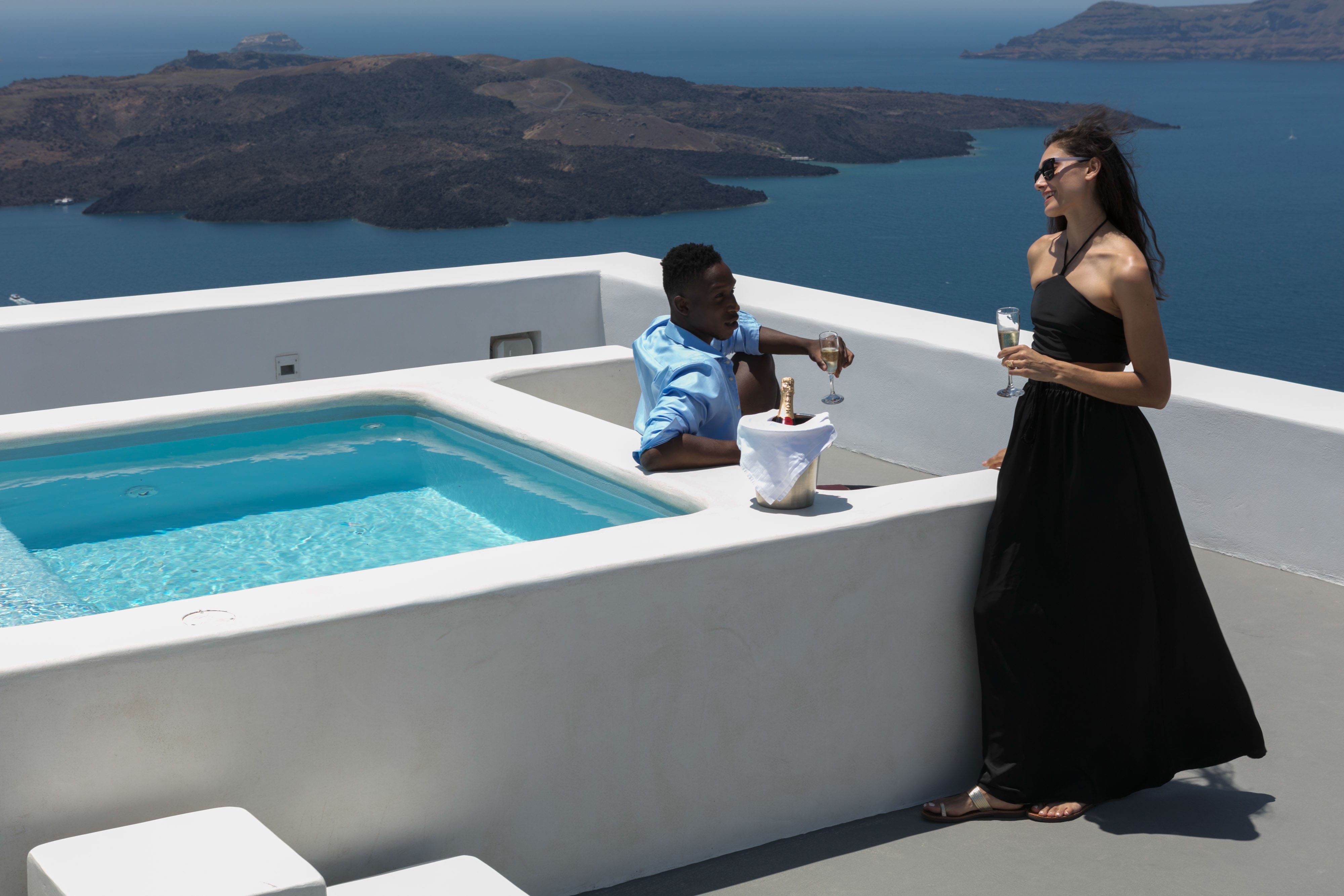 a person in a black dress standing by a pool