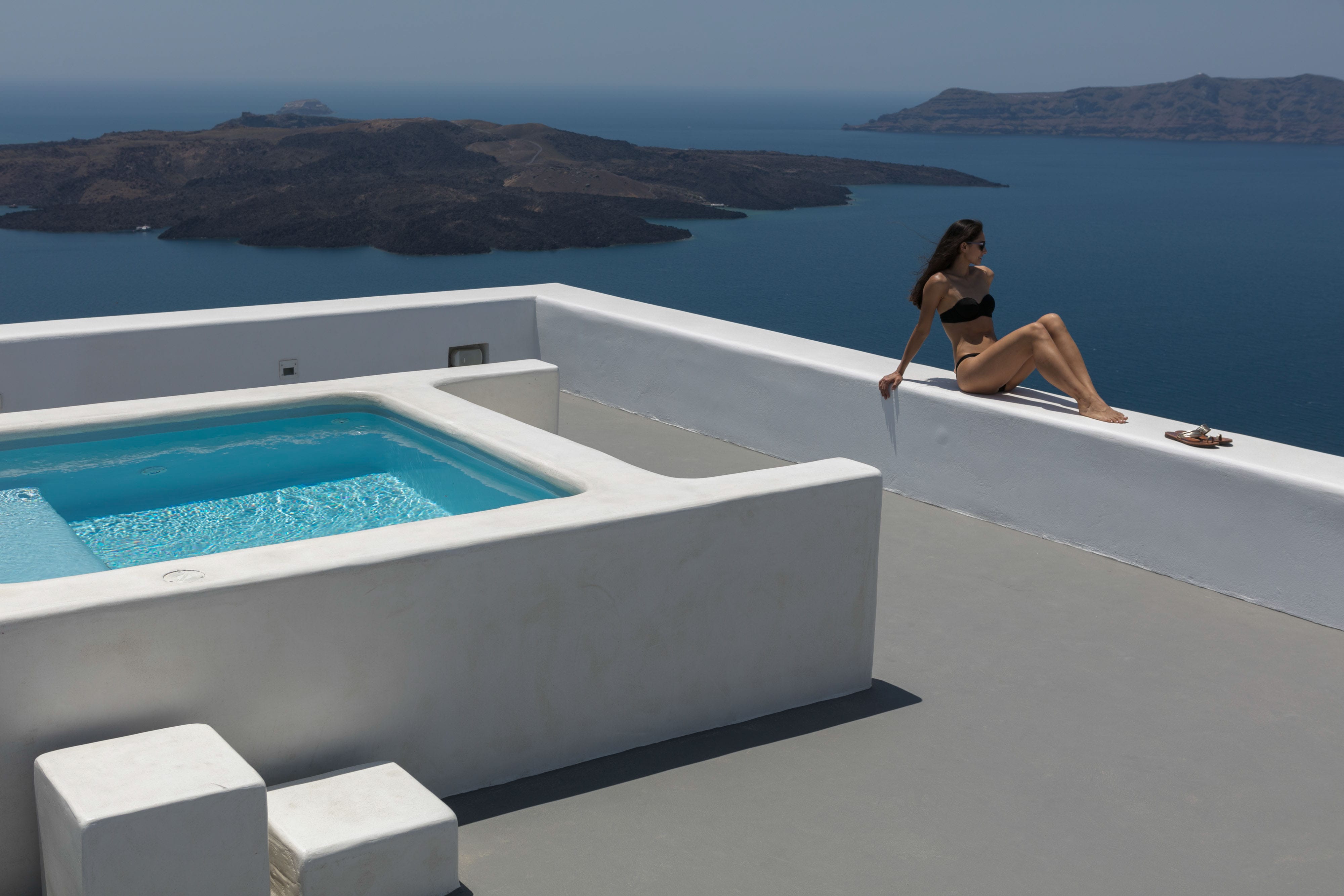 a person sitting on a ledge of a pool