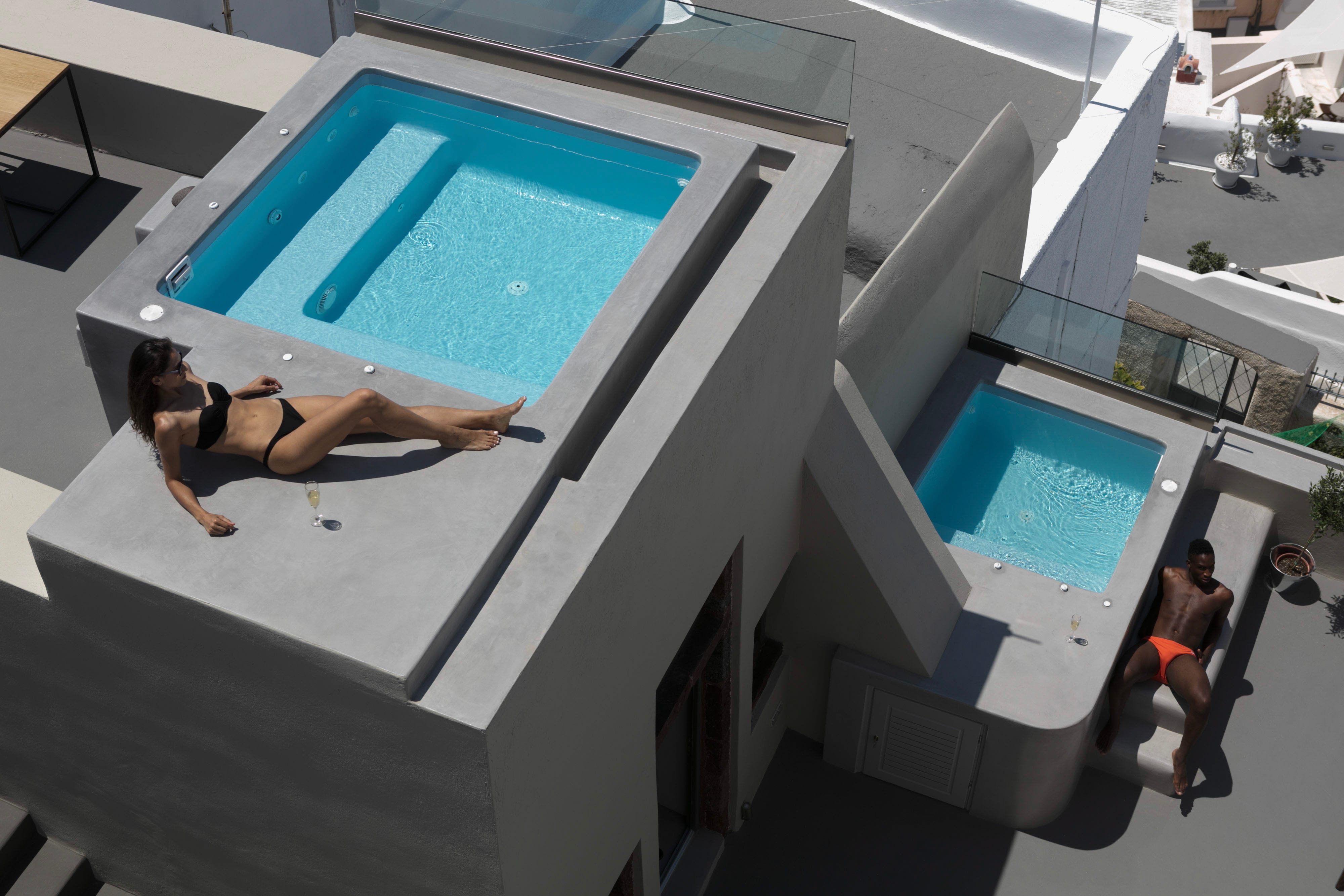 a person lying on a rooftop of a building with a pool