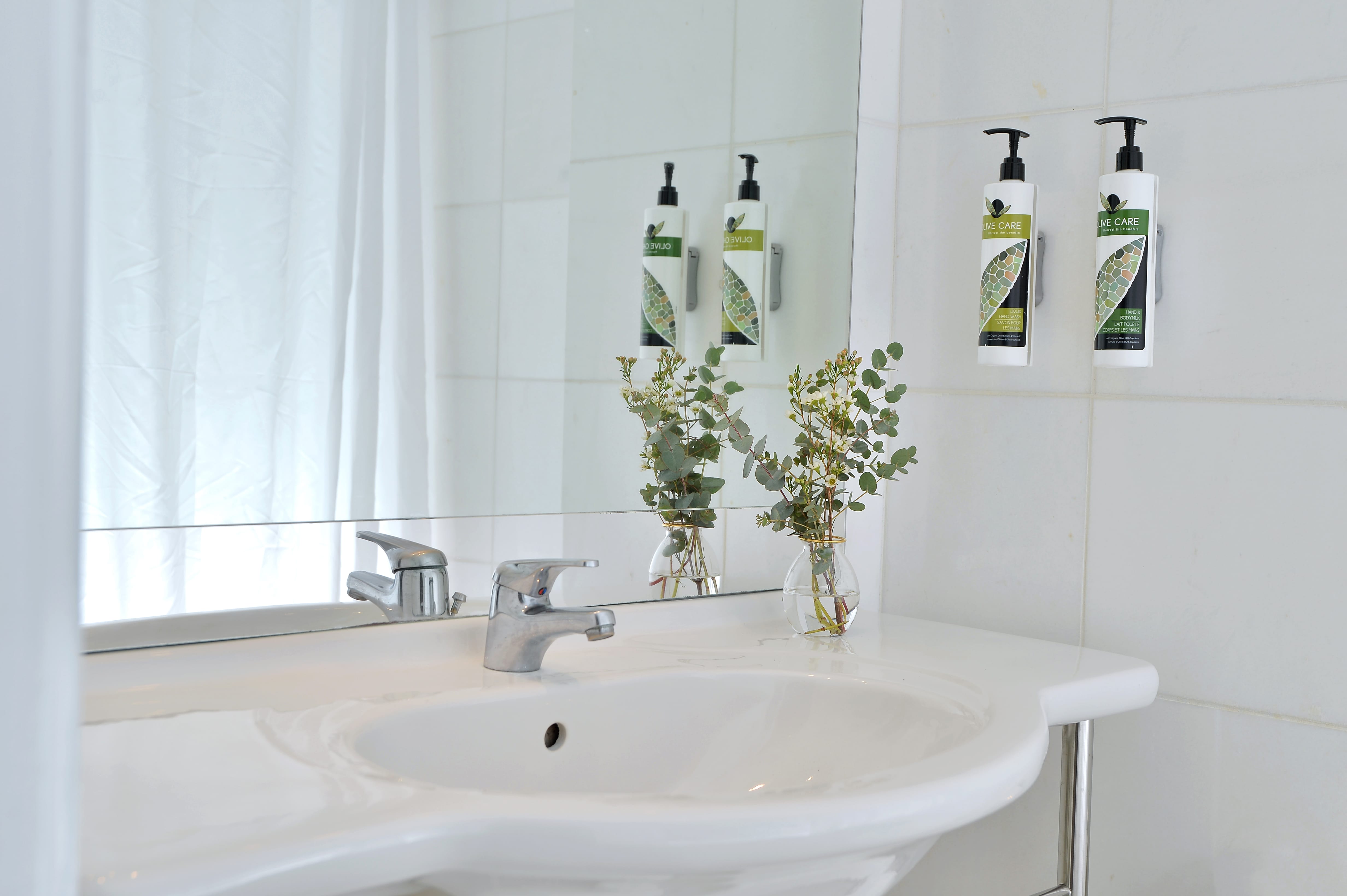 a bathroom sink with a plant in a vase