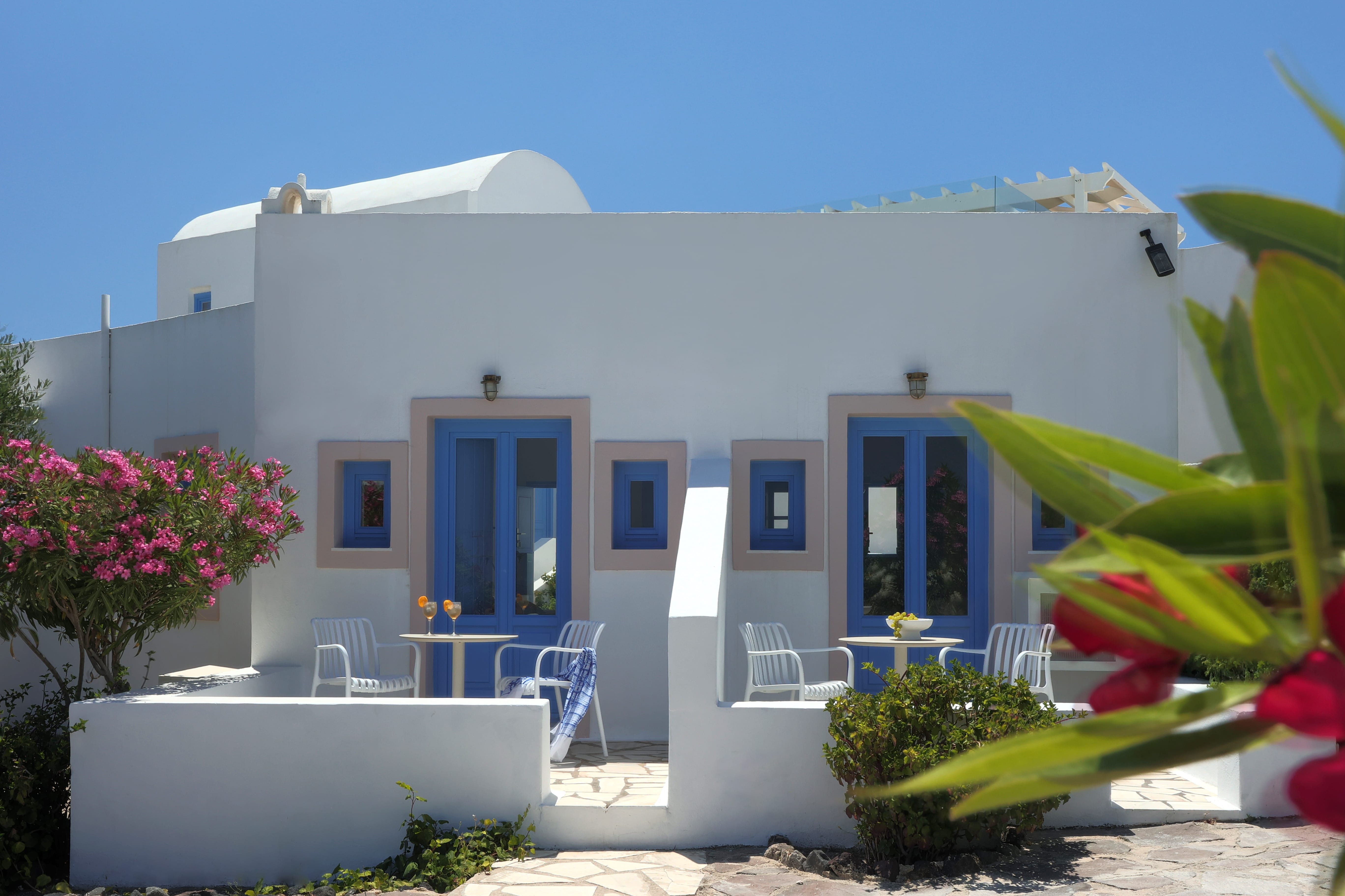 a white house with blue doors and chairs