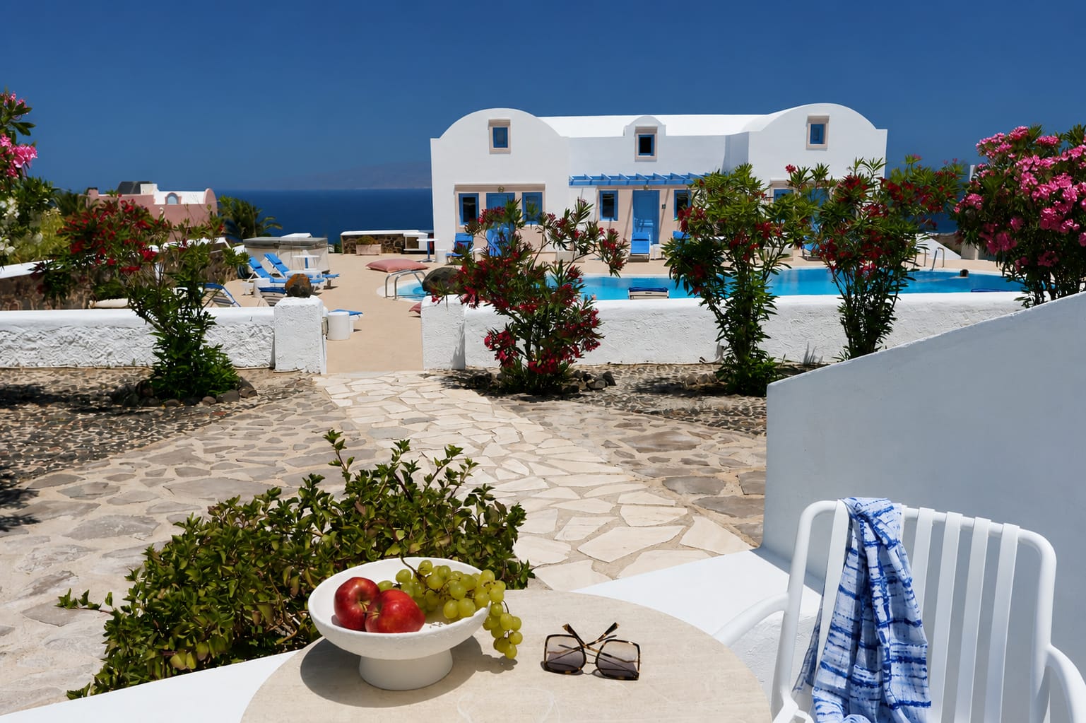 a white house with a pool and a bowl of fruit