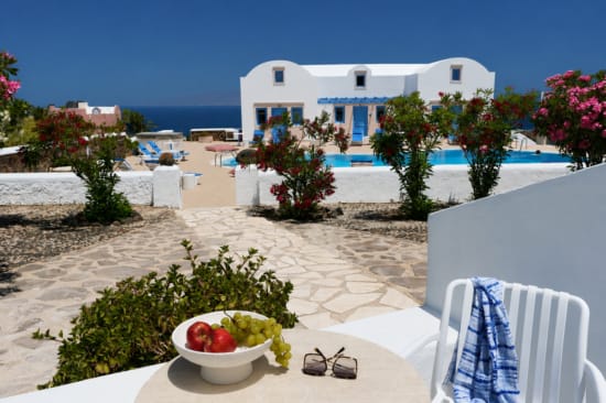 a white house with a pool and a bowl of fruit