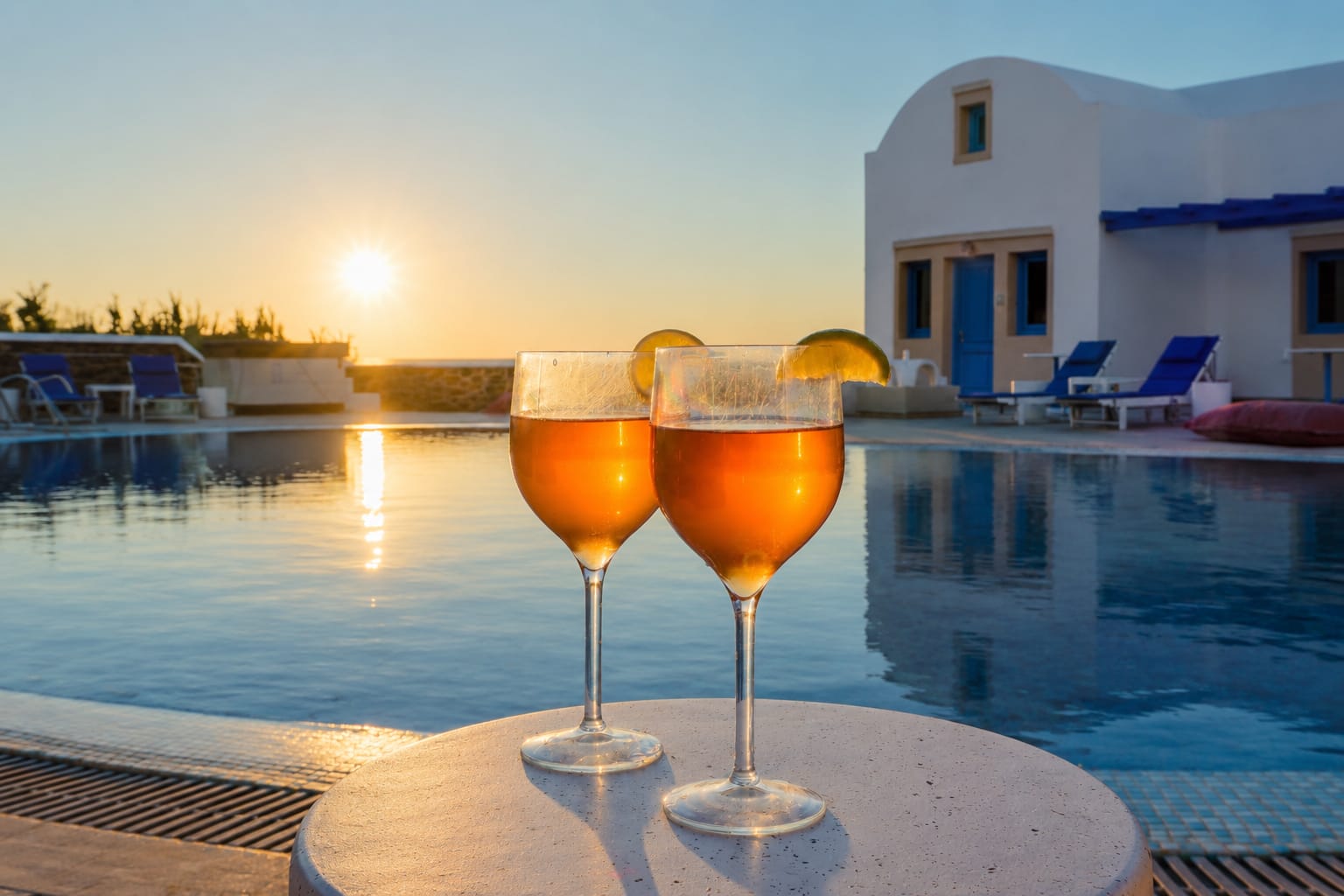two glasses of wine on a table by a pool