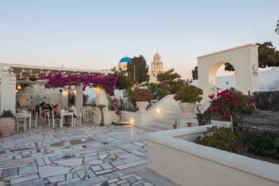a patio with white walls and white tables and chairs