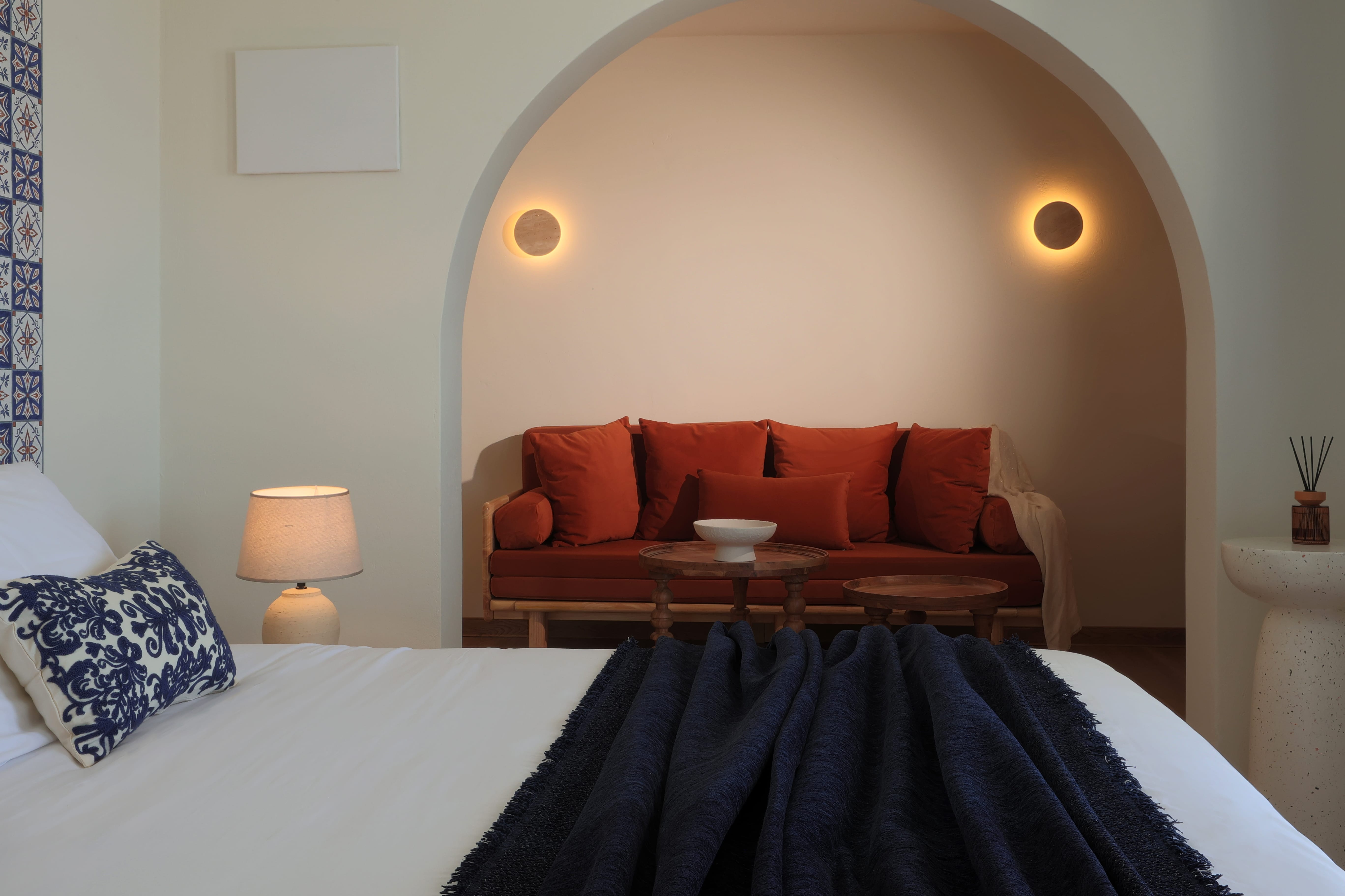 a bed with a blue blanket and a red couch in a room