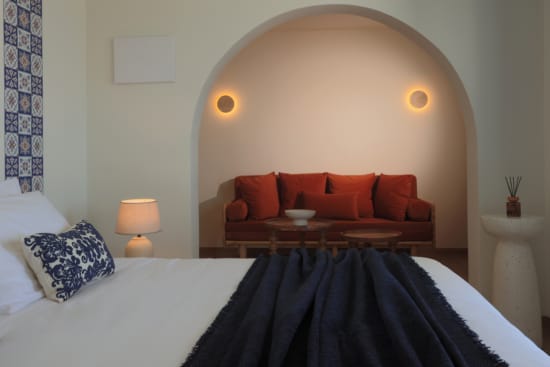 a bed with a blue blanket and a red couch in the background