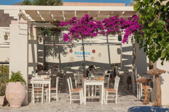 a white outdoor restaurant with tables and chairs
