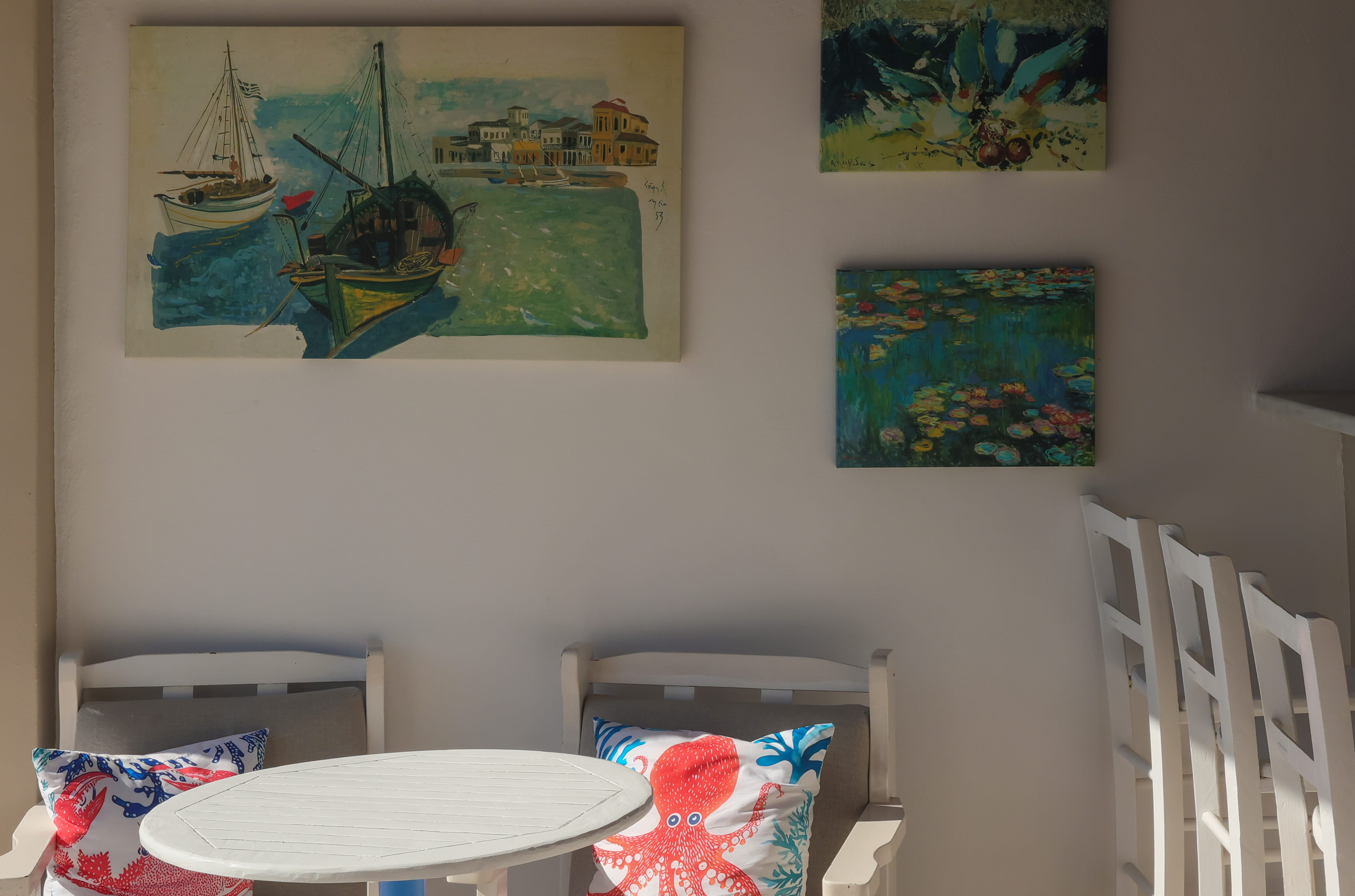 a table and chairs with paintings on the wall