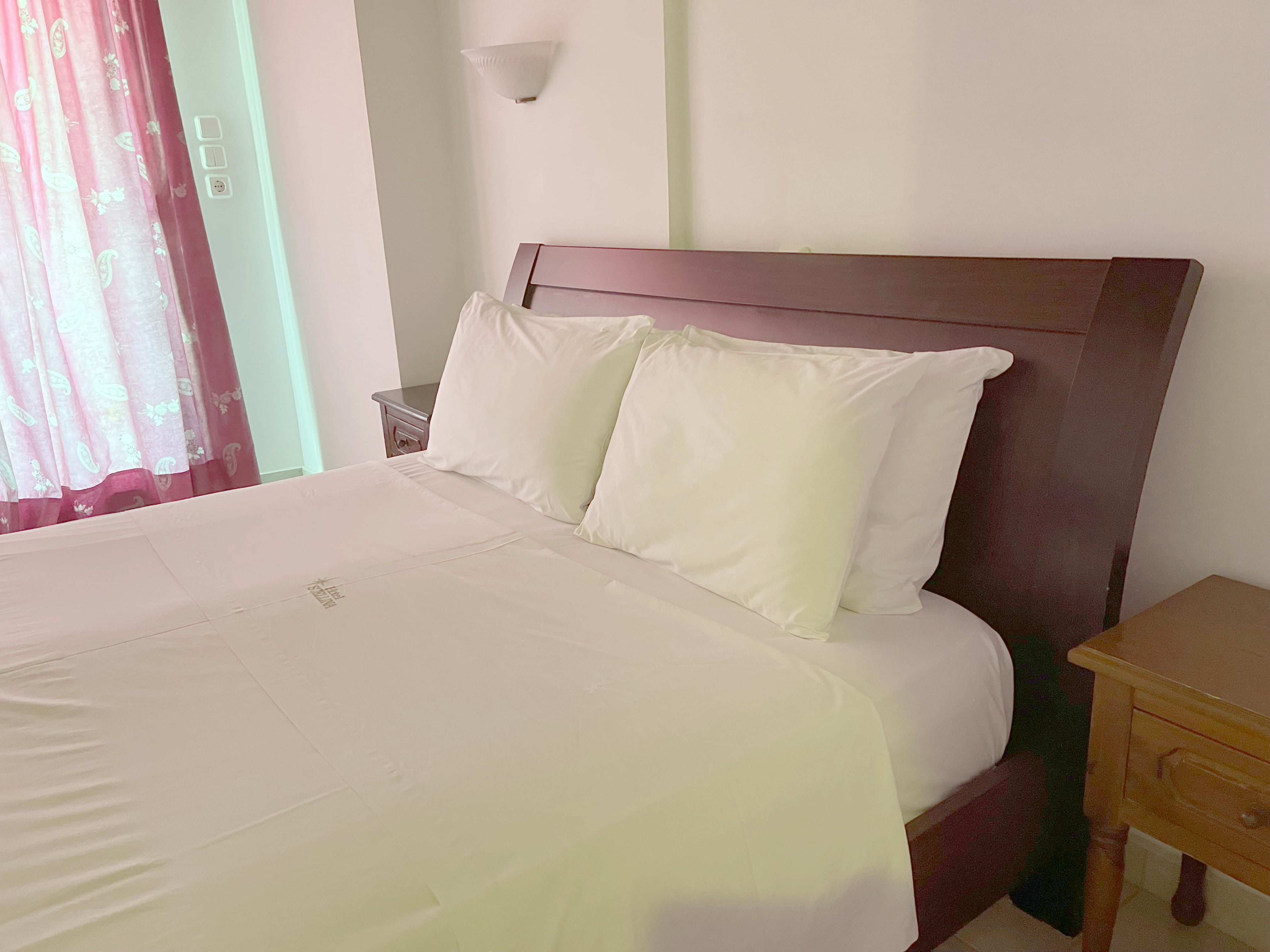 a bed with white sheets and pillows