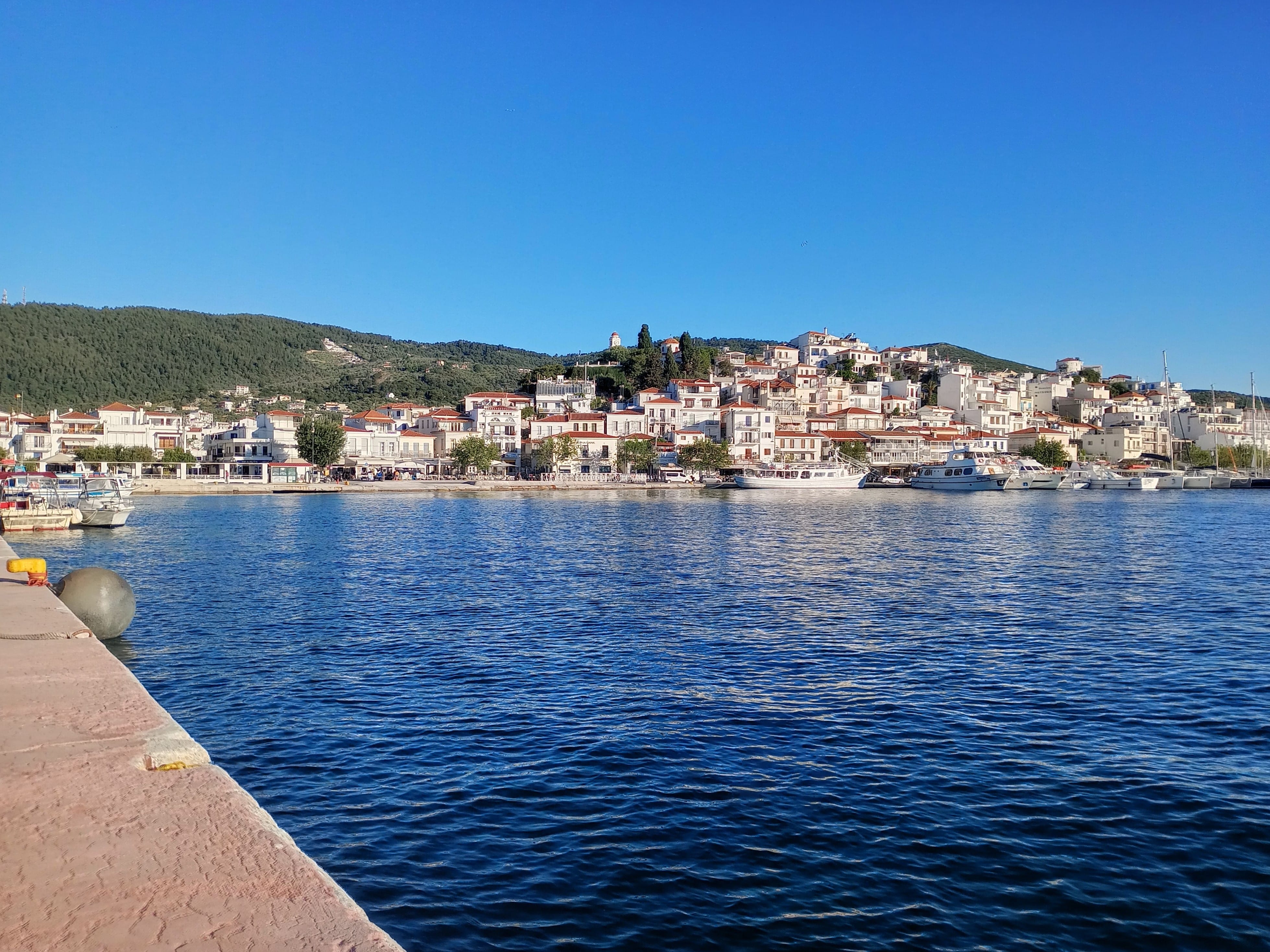 a body of water with buildings and hills in the background