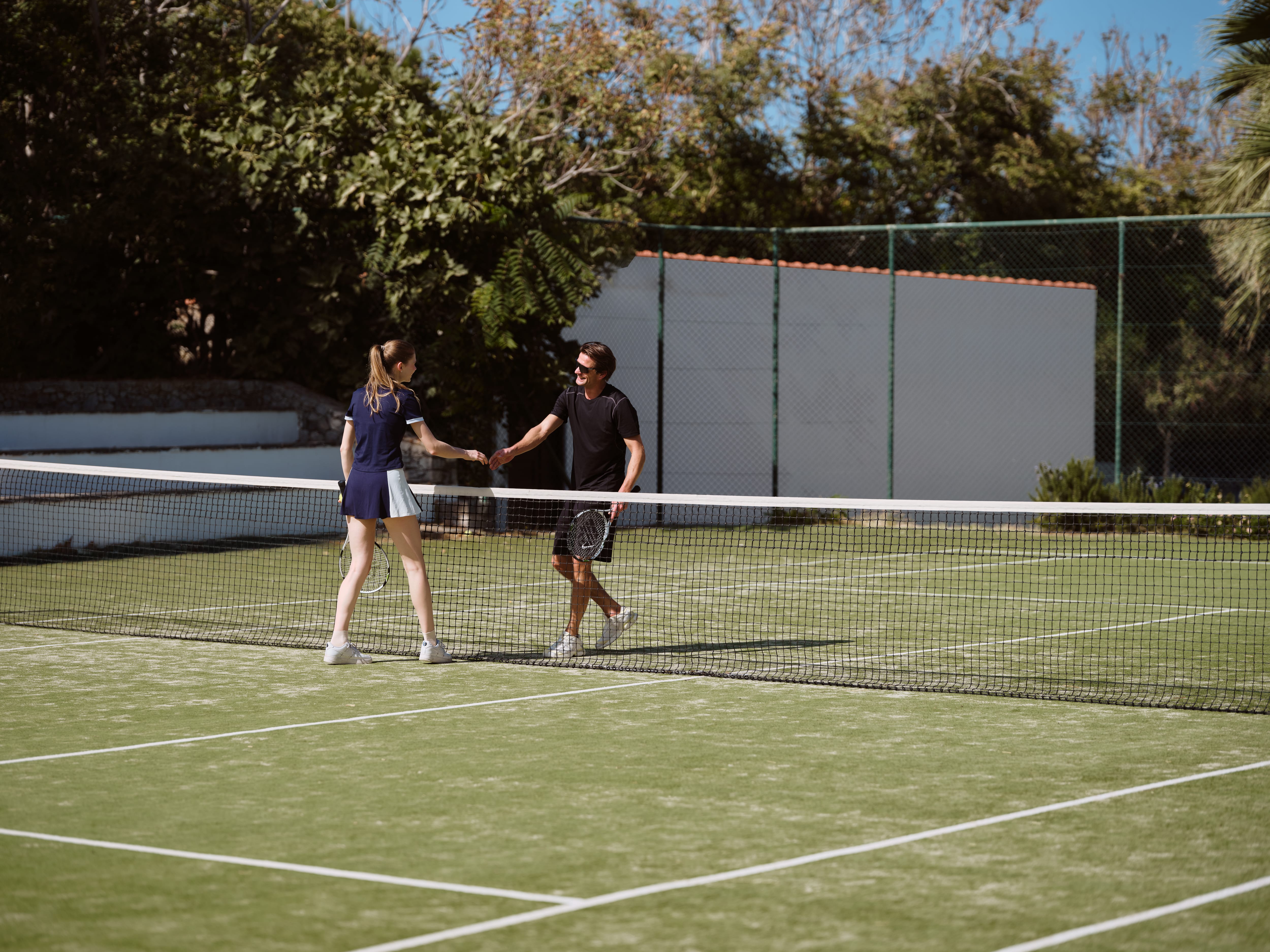a person and person shaking hands on a tennis court