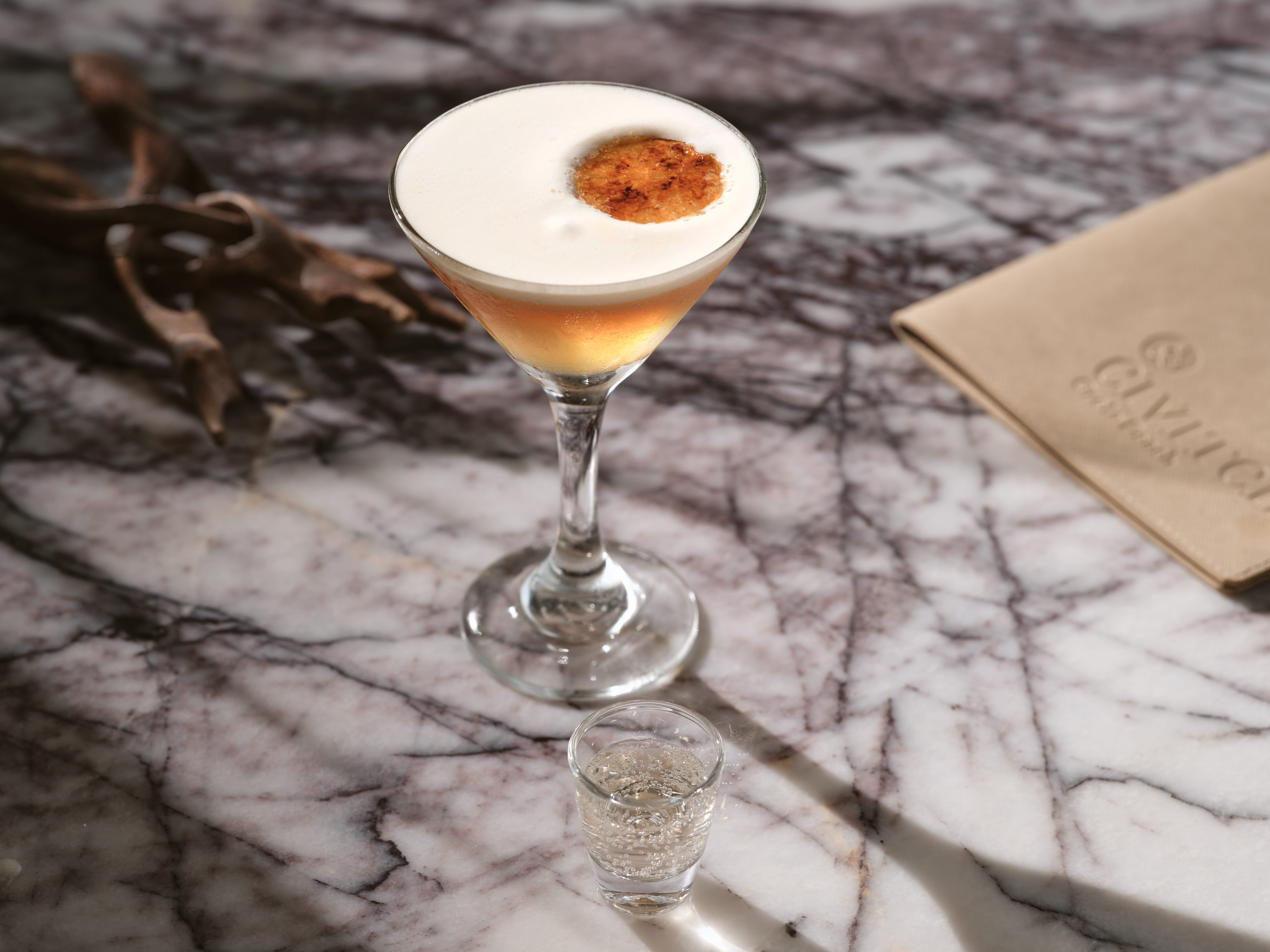 a glass with a drink on a marble table