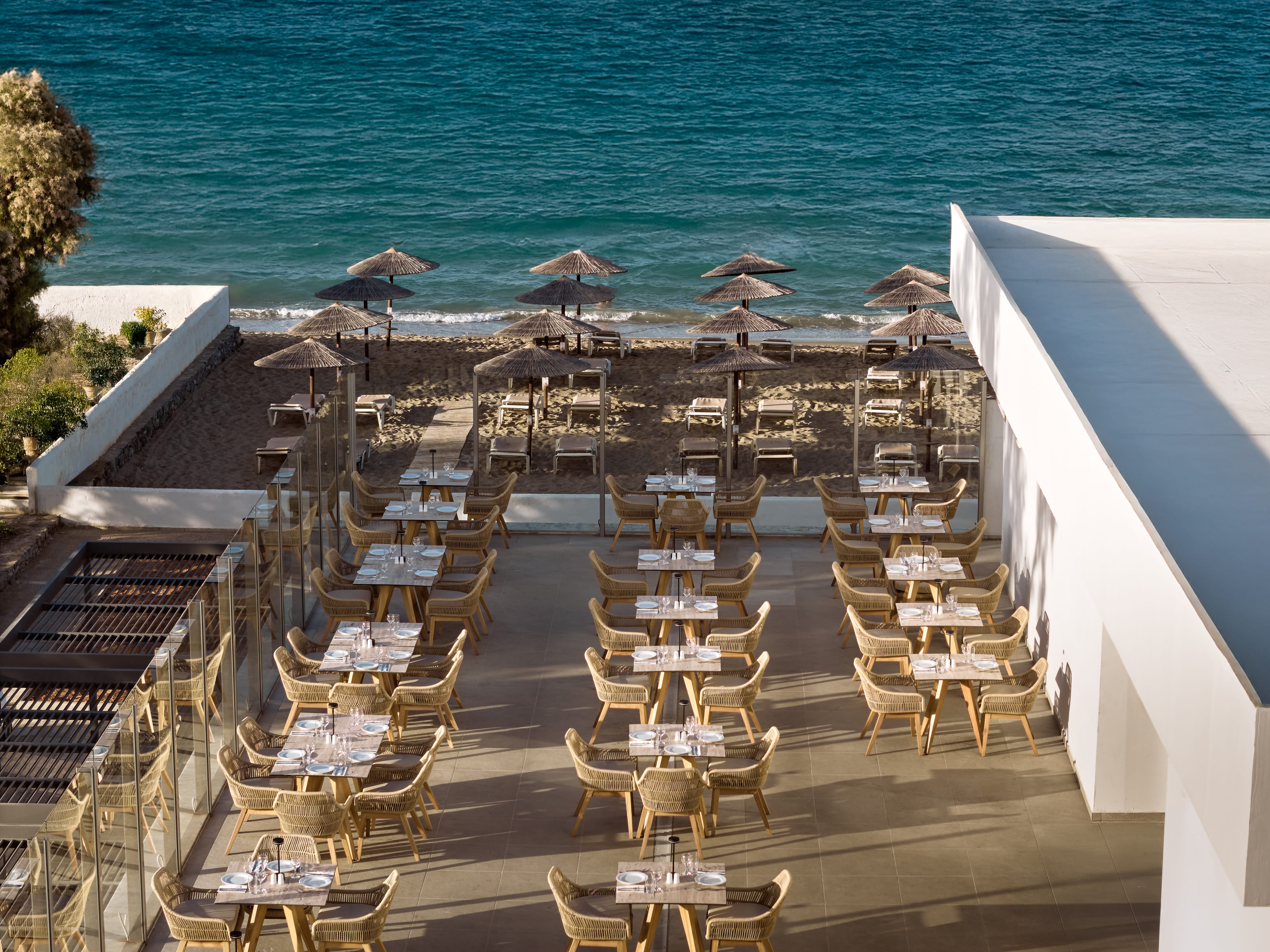 a restaurant with tables and umbrellas on the beach