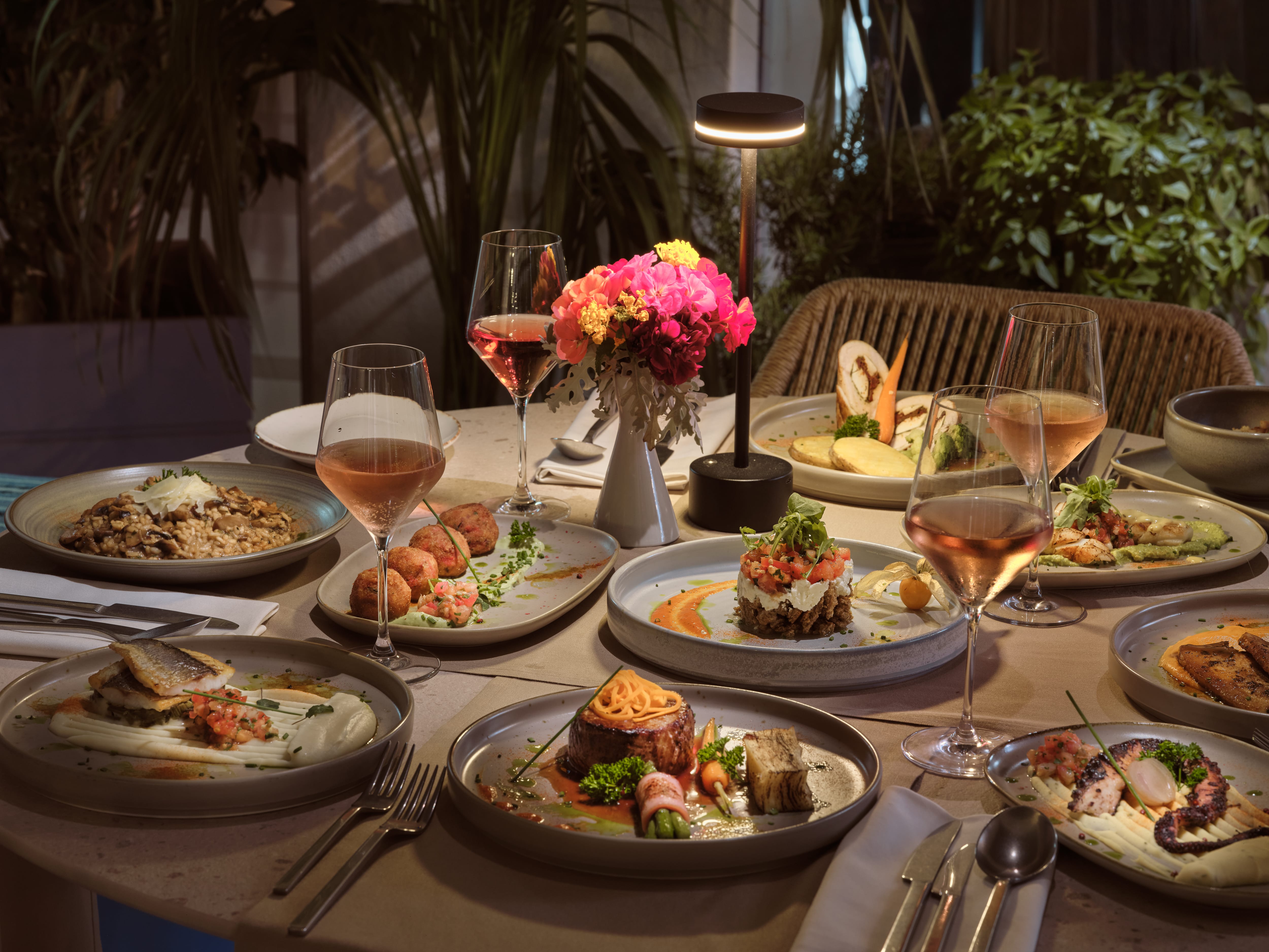 a table with plates of food and wine glasses