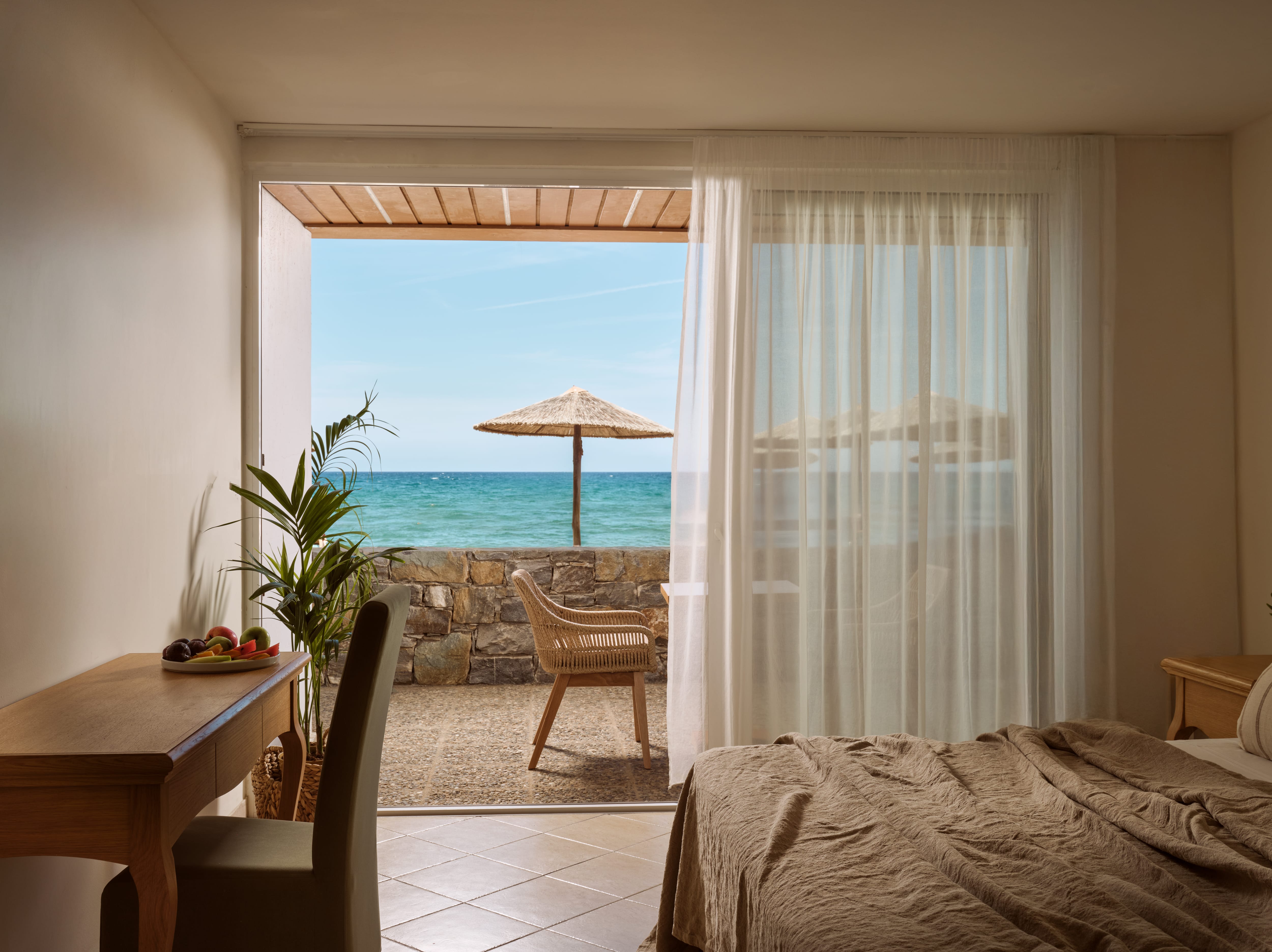 a room with a bed and a table and chairs and a beach view