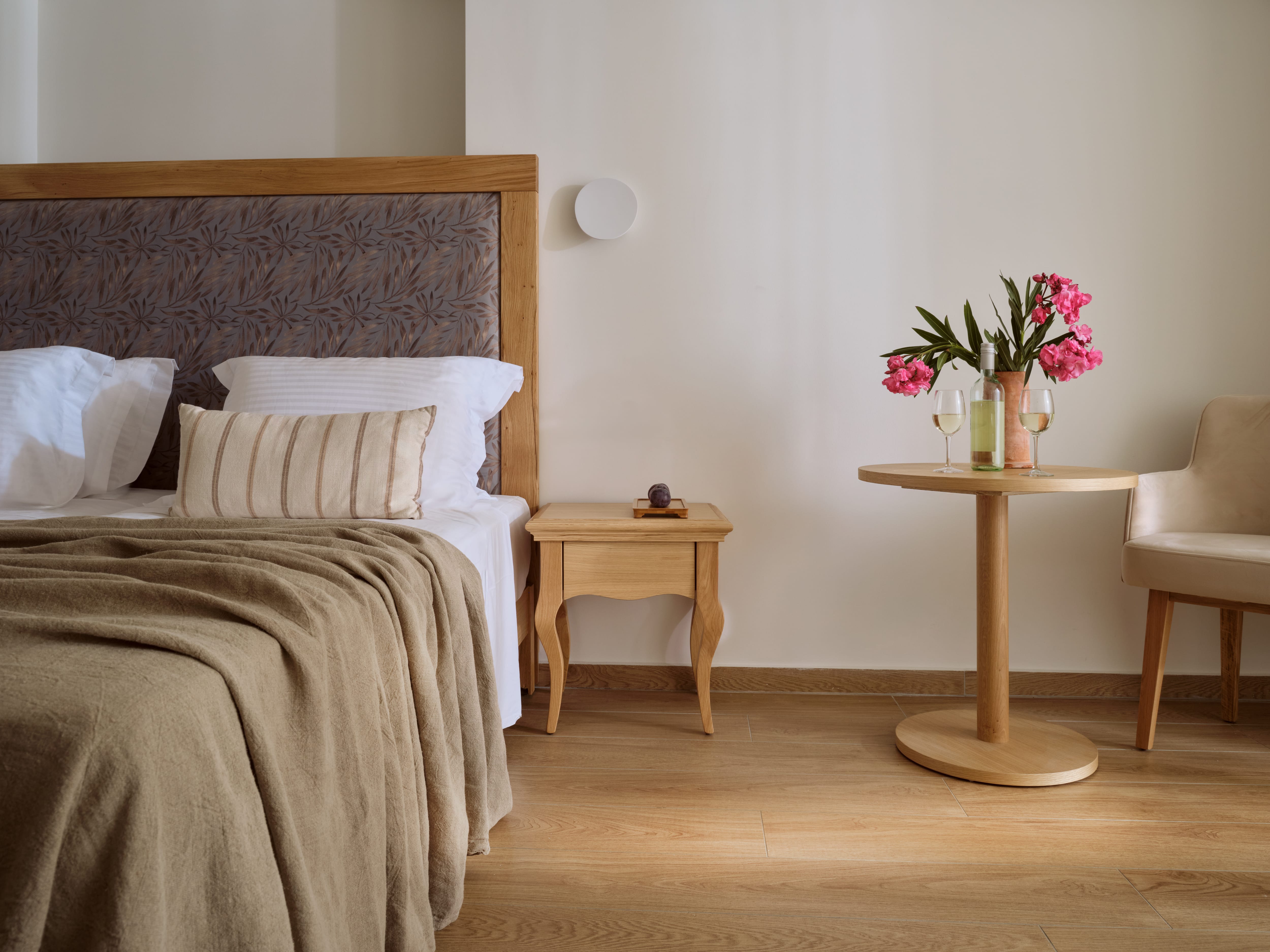 a bed with a brown headboard and a small table with pink flowers