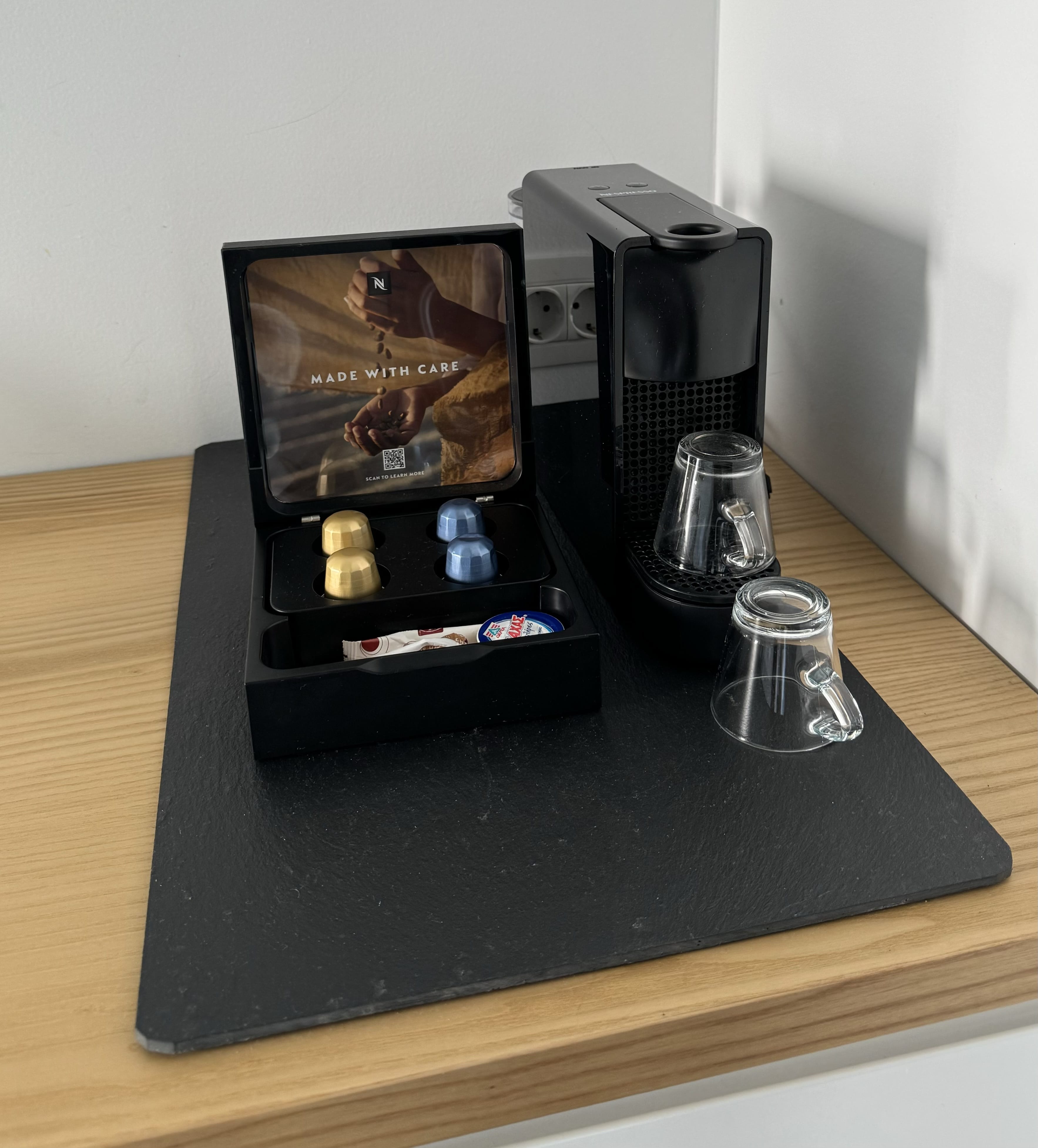 a black rectangular object with a screen and a glass on a wooden surface