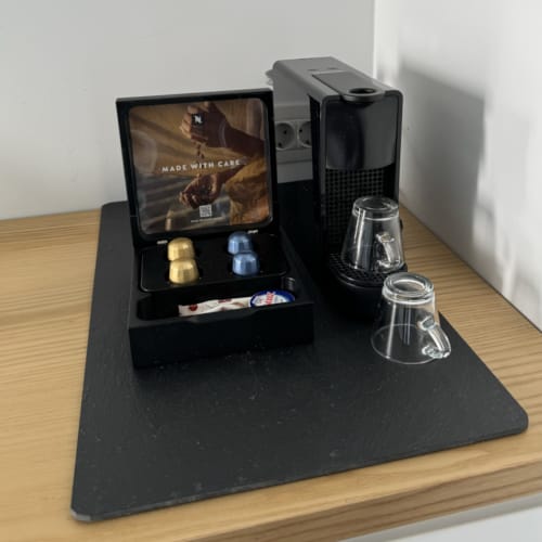 a black rectangular object with a screen and a glass on a wooden surface