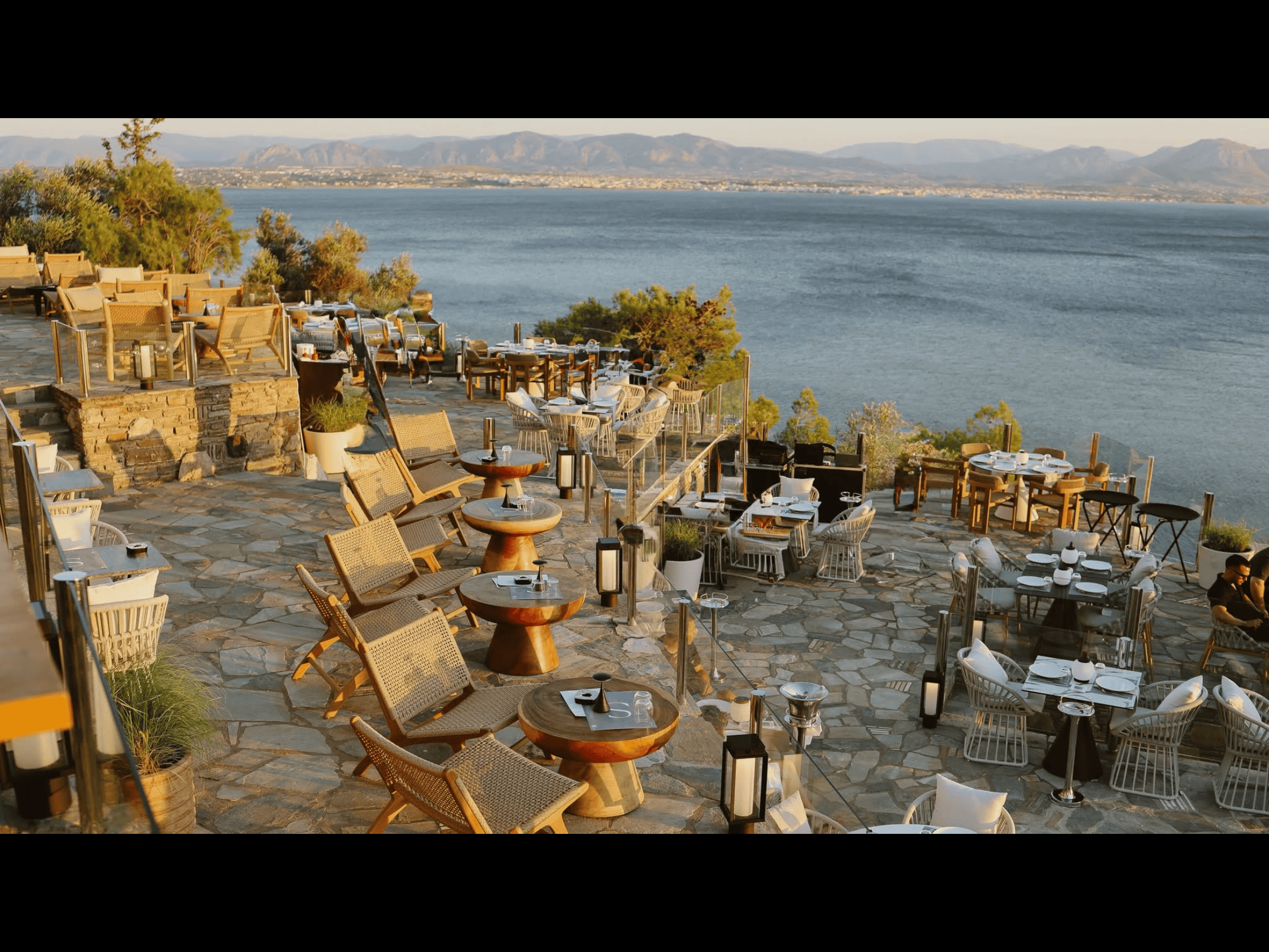 a restaurant with tables and chairs overlooking a body of water