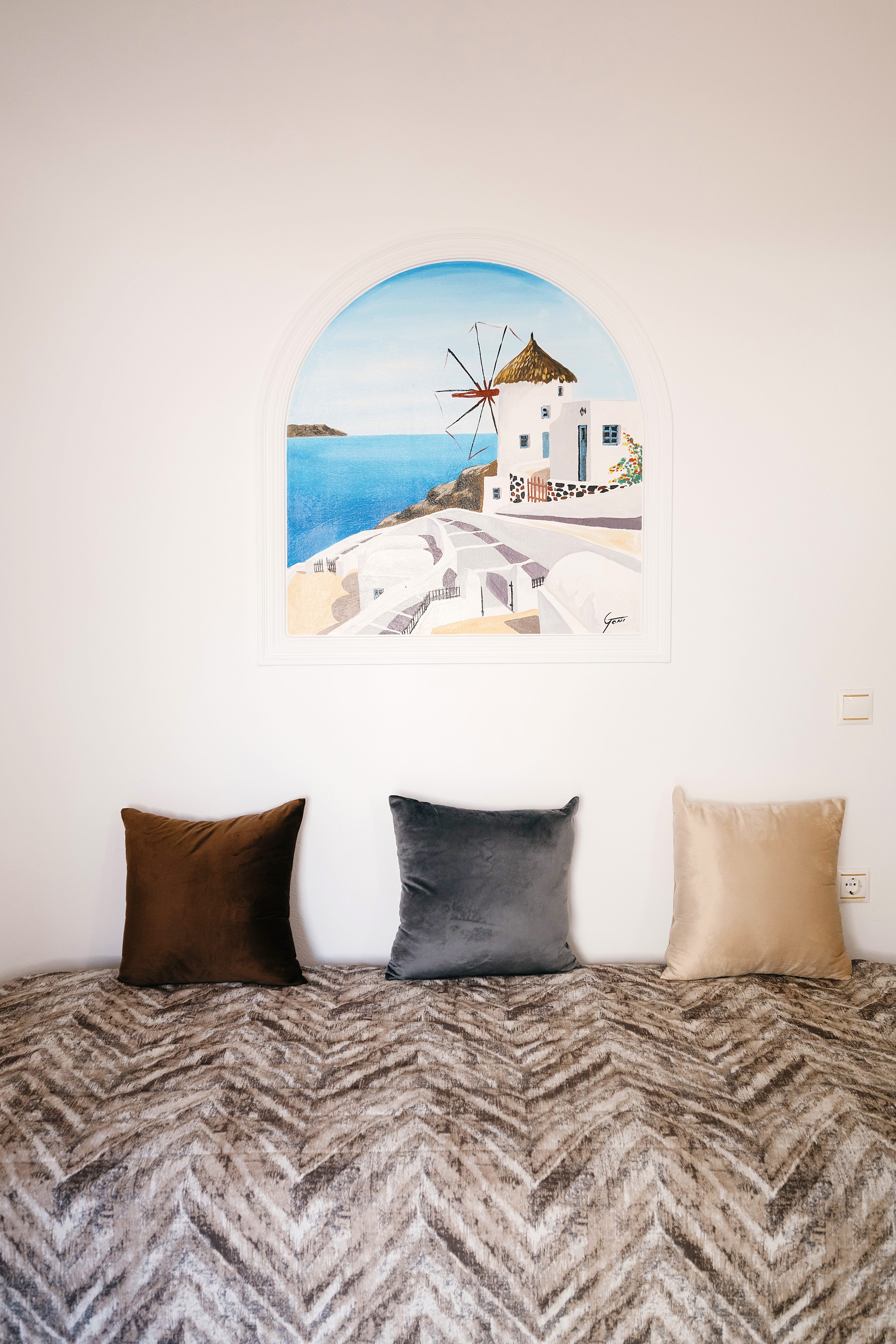 a bed with pillows and a painting on the wall
