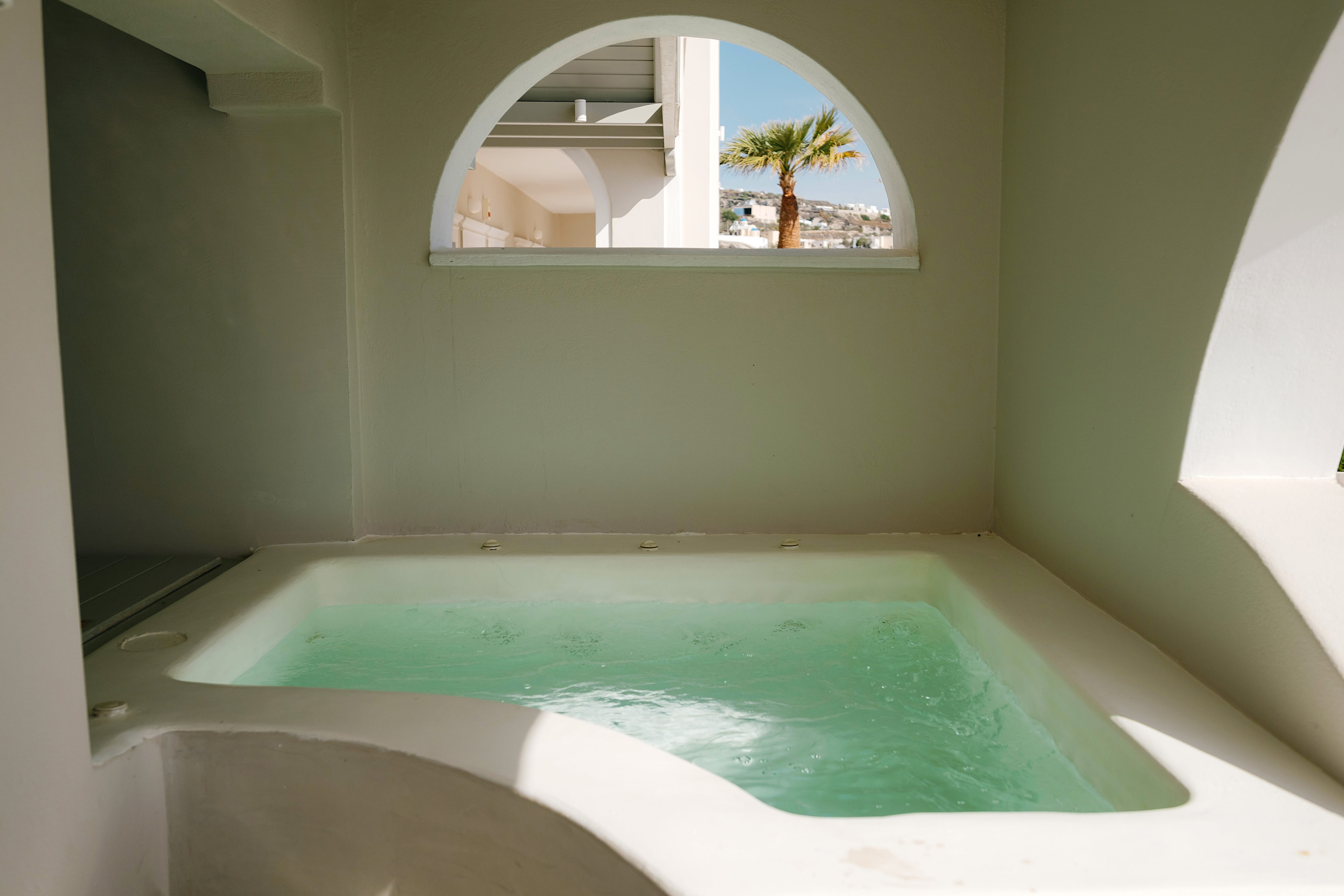 a large indoor bathtub with a round mirror above it