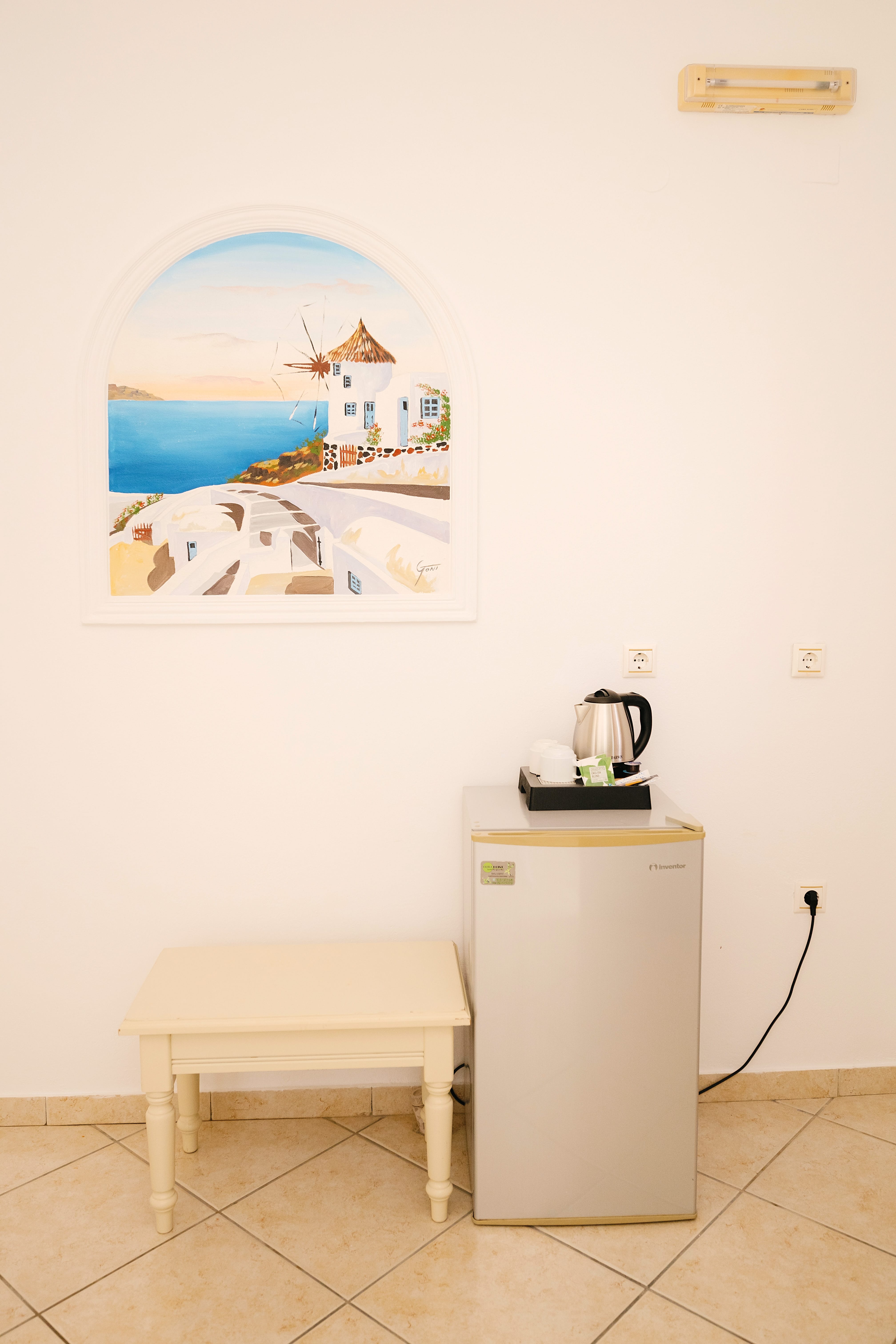a white wall with a painting on it and a white table with a white cabinet and a white