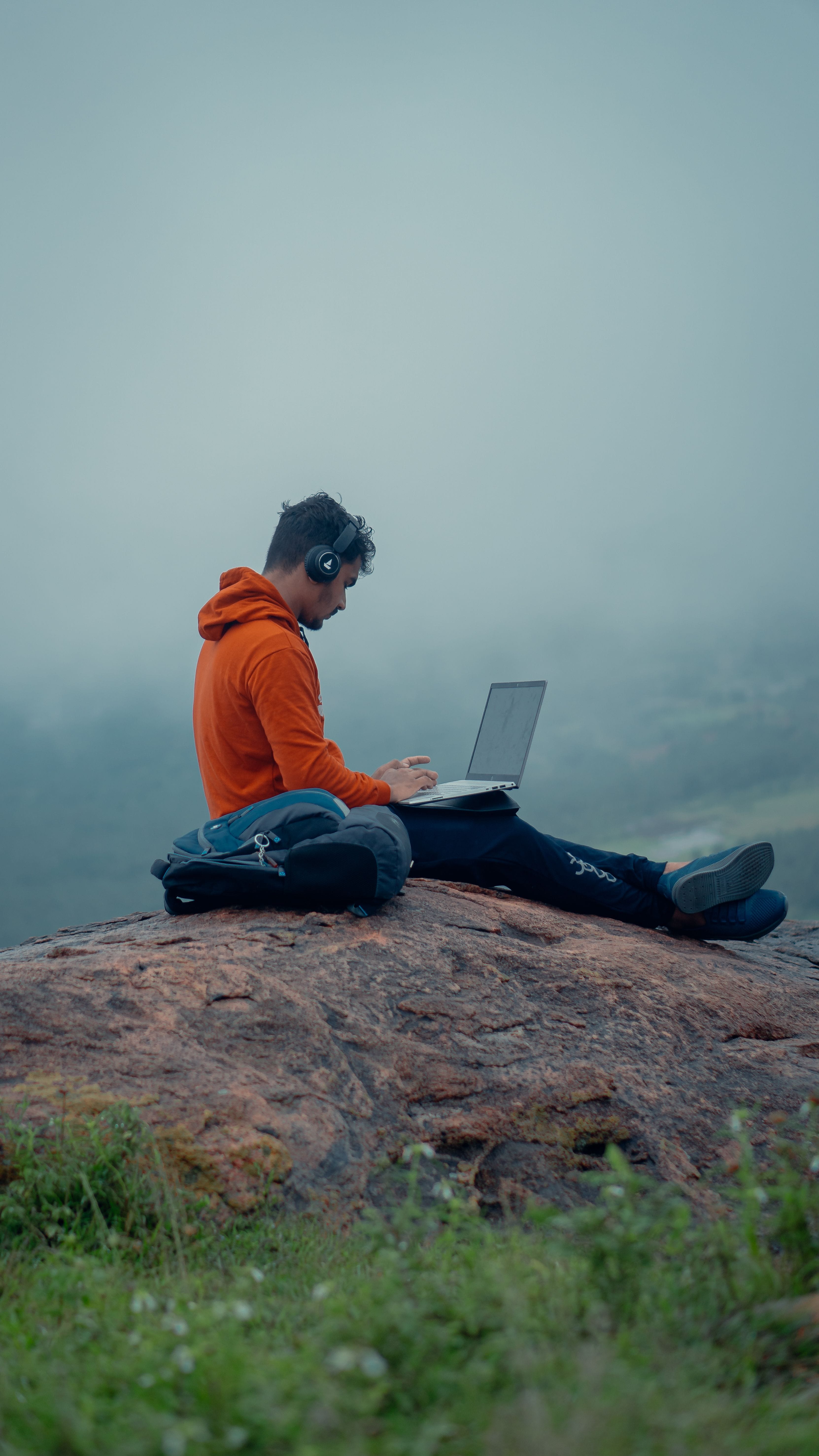 a person sitting on a rock with a laptop