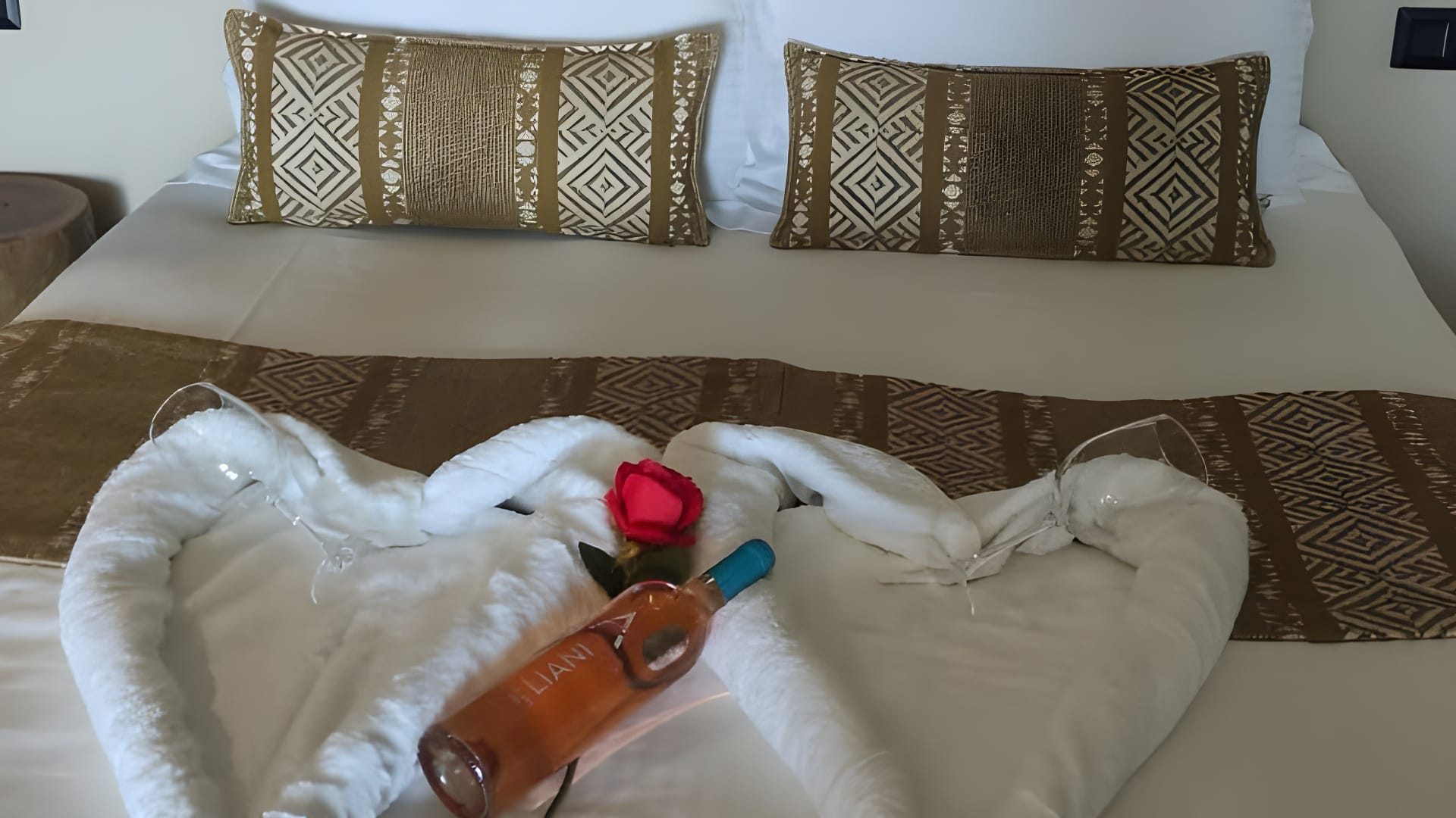 a bottle and rose on a bed