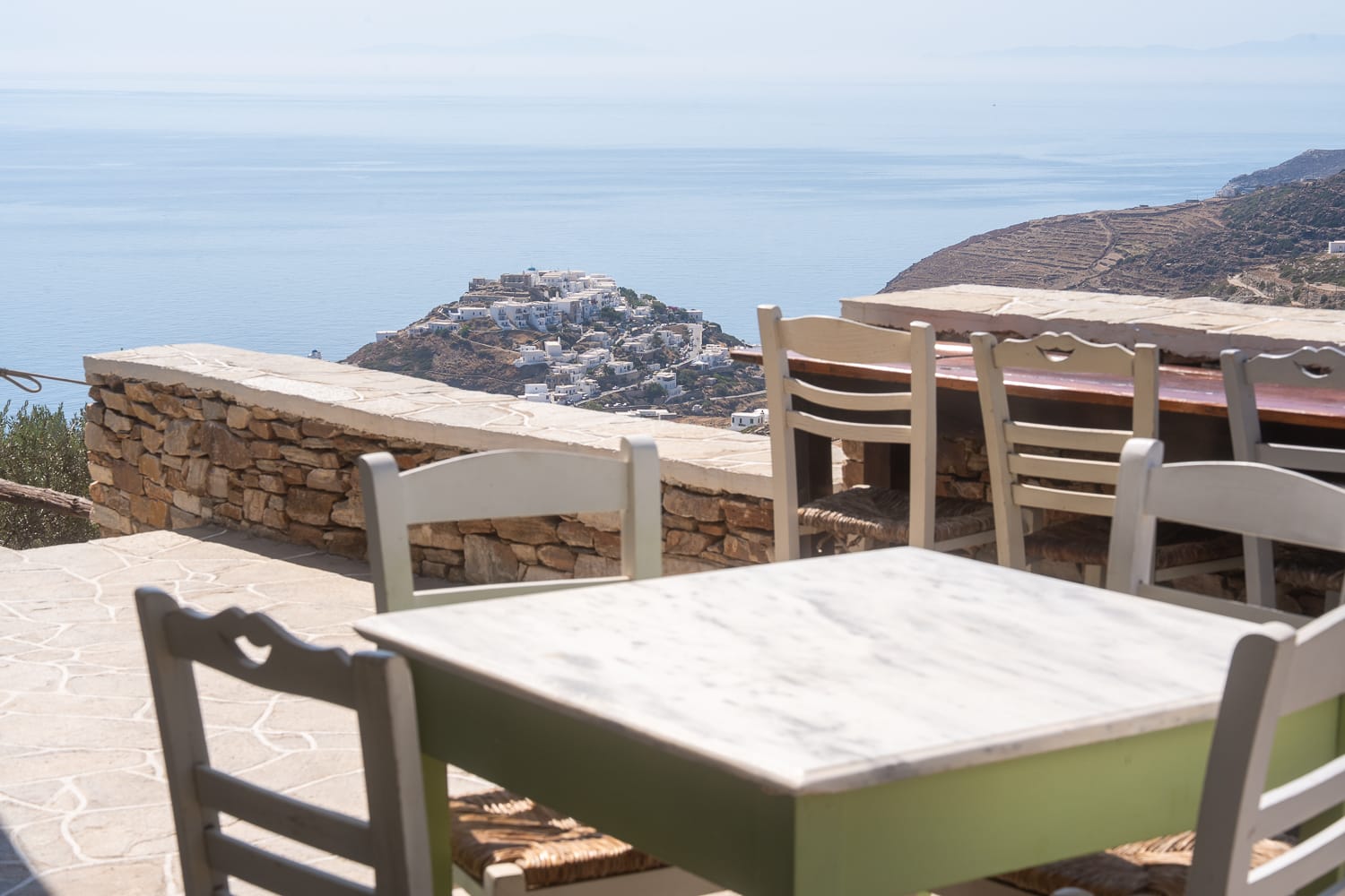 a table and chairs on a terrace overlooking the sea