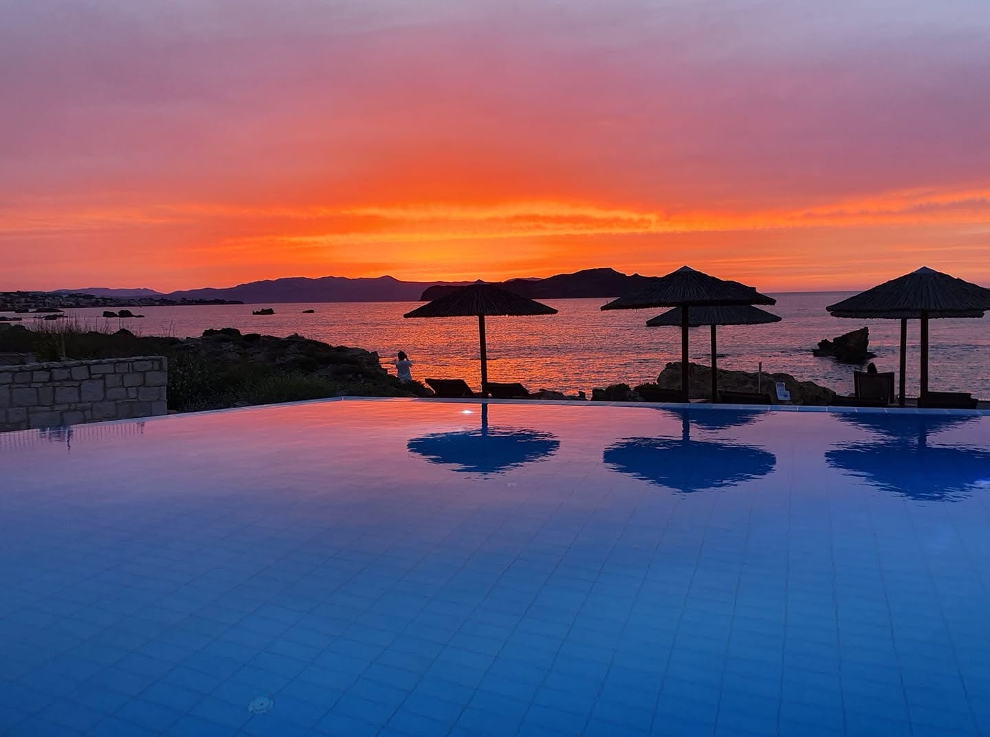 a pool with umbrellas and a sunset