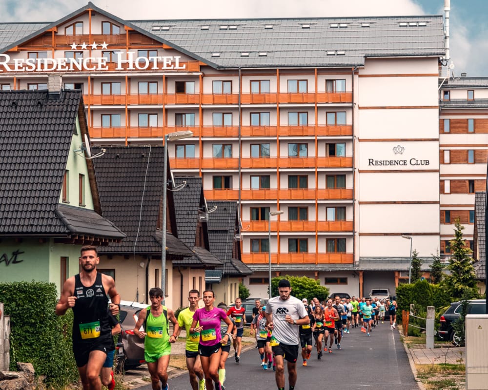 a group of people running on a road in front of a building