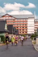 a group of people running on a road in front of a building