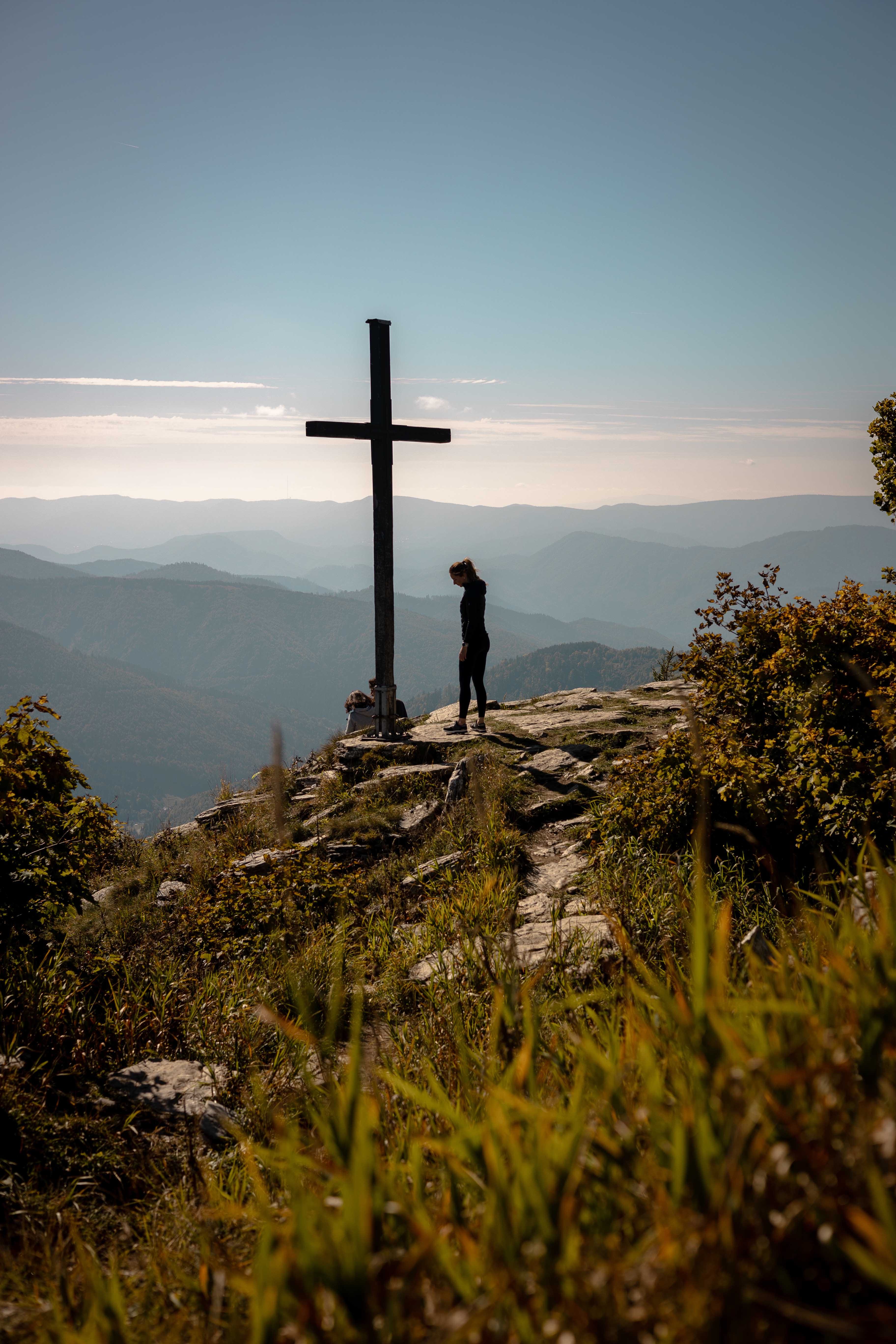 a person standing on a rock with a cross on top of it