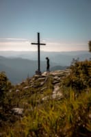 a person standing on a rock with a cross on top of it