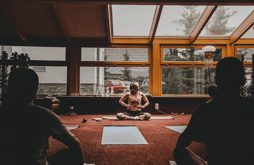 a group of people sitting in a room with windows and a person sitting on a bench
