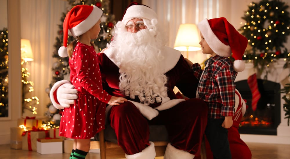 a person in a santa suit sitting next to a child in a santa garment
